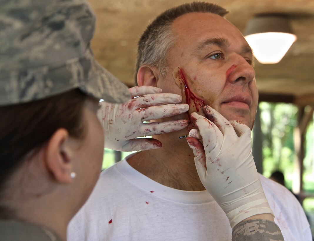 Jeff Ewy, volunteer achievement coordinator  with Cub Scout Pack 753, patiently holds still as Airman First Class Katherine Martin,  a 932nd Airlift Wing Aeromedical Staging Squadron medical technician,  applies a prosthetic "fake" or "make up" wound during a mass casuality exercise recently at Scott Air Force Base.  Other medical technicians would check on him later as a simulated patient at the 932nd Airlift Wing event.  (U.S. Air Force photo/ Tech. Sgt. Christopher Parr) 