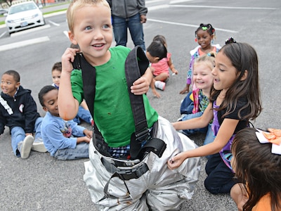 Nathan Hascall, a pre-school student at the Child Development Center, dons fire fighters’ personal protective equipment Oct. 9 at Joint Base San Antonio-Randolph. Fire Prevention Week was established to commemorate the Great Chicago Fire, the tragic 1871 conflagration that killed more than 250 people, left 100,000 homeless, destroyed more than 17,400 structures and burned more than 2,000 acres. The fire began Oct. 8, but continued into and did most of its damage Oct. 9, 1871. (U.S. Air Force photo by Benjamin Faske)