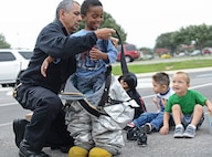 Jesus Lopez, 902nd Fire and Emergencies Services inspector, explains the importance of personal protective equipment to Chase Siatita, a pre-school student from the child development center Oct. 9 at Joint Base San Antonio-Randolph. Fire Prevention Week was established to commemorate the Great Chicago Fire, the tragic 1871 conflagration that killed more than 250 people, left 100,000 homeless, destroyed more than 17,400 structures and burned more than 2,000 acres. The fire began Oct. 8, but continued into and did most of its damage Oct. 9, 1871. (U.S. Air Force photo by Benjamin Faske)