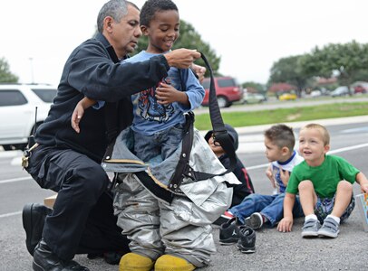 Jesus Lopez, 902nd Fire and Emergencies Services inspector, explains the importance of personal protective equipment to Chase Siatita, a pre-school student from the child development center Oct. 9 at Joint Base San Antonio-Randolph. Fire Prevention Week was established to commemorate the Great Chicago Fire, the tragic 1871 conflagration that killed more than 250 people, left 100,000 homeless, destroyed more than 17,400 structures and burned more than 2,000 acres. The fire began Oct. 8, but continued into and did most of its damage Oct. 9, 1871. (U.S. Air Force photo by Benjamin Faske)