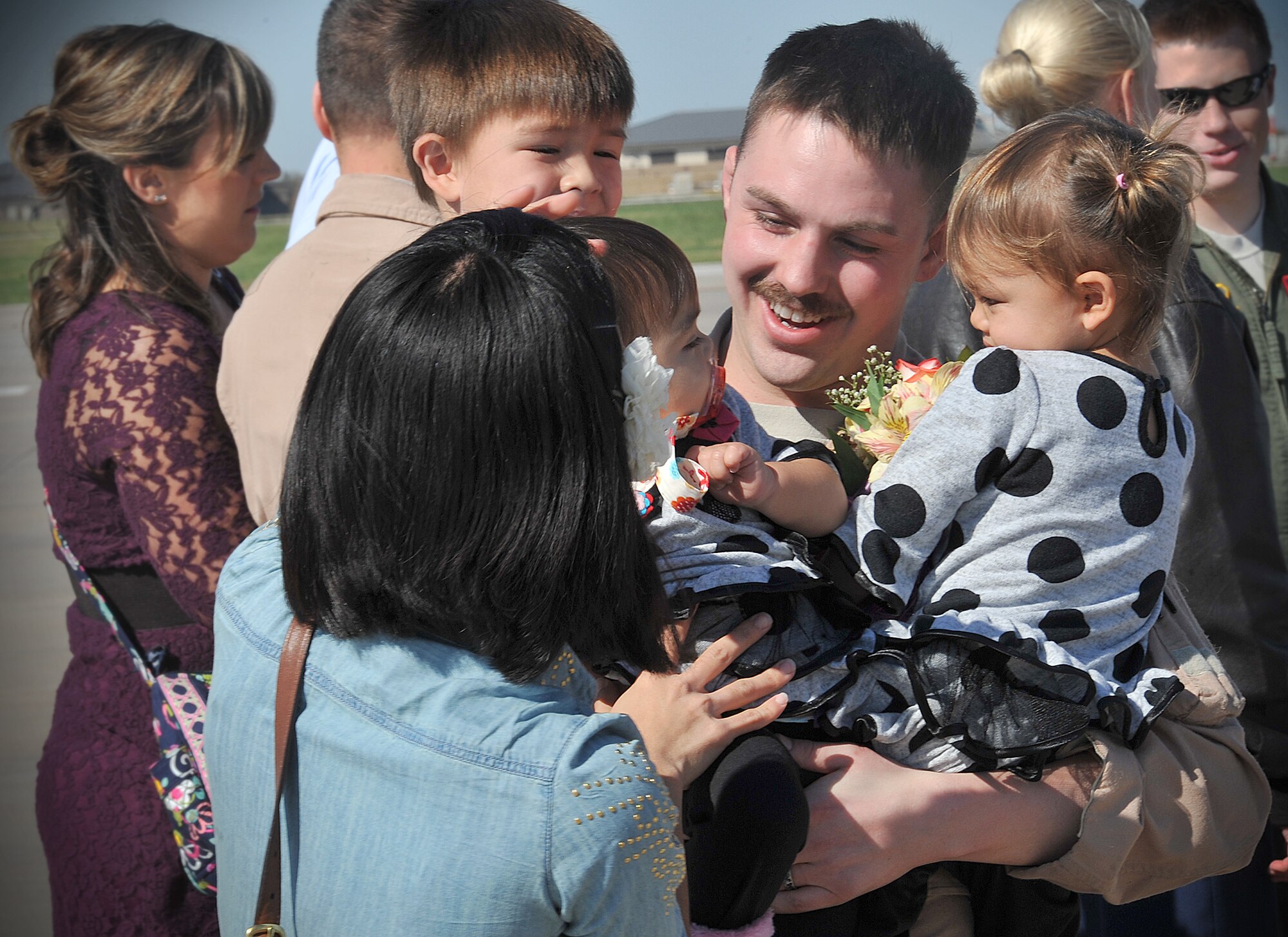 Staff Sgt. Cody Beverly, 350th Air Refueling Squadron boom operator, embraces his children and wife after returning from a deployment Oct. 15, 2012, McConnell Air Force Base, Kan. More than 30 Airmen, including Beverly, returned from deployments of various lengths in the Middle East. Currently 537 active duty, reservists and guardsmen are deployed to a total of 23 locations worldwide. (U.S. Air Force photo/Airman 1st Class Maurice A. Hodges)