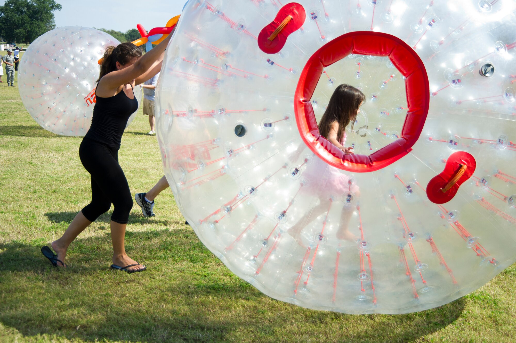 Flor Rodriguez pushes an inflatable hamster ball with her daughter, Nicole Rodriguez, 4, inside helping her pick up speed at the dorm block party Oct. 12, 2012, at the field between the Exchange and Shaw House, Keesler Air Force Base, Miss. Nicole's stepfather is Airman 1st Class Alberto Rodriguez, 81st Inpatient Operation Squadron.  (U.S. Air Force photo by Adam Bond)
