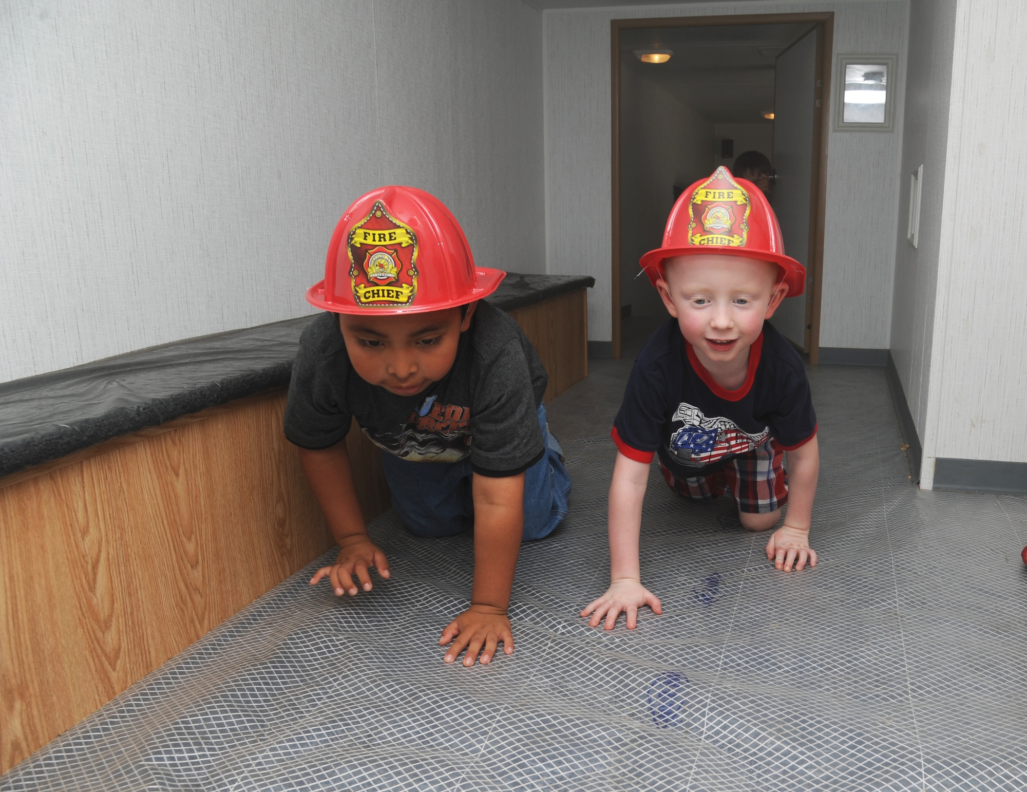 Javier Tate, 6, and Jackson Dossett, 4, crawl safely through a fire safe house during the Keesler Fire Department’s open house Oct. 13, 2012, Keesler Air Force Base, Miss.  The event was held on the final day of fire prevention week during which the fire department conducted random fire drills throughout the base, toured various facilities with Sparky the Fire Dog, passed out fire safety handouts and fire hats for children and provided stove and fire extinguisher demonstrations.  Javier’s mom is Lt. Col. Rashone Tate, 81st Communications Squadron commander.  Jackson’s mom is Capt. Laura Dossett, 81st Surgical Operations Squadron.  (U.S. Air Force photo by Kemberly Groue)