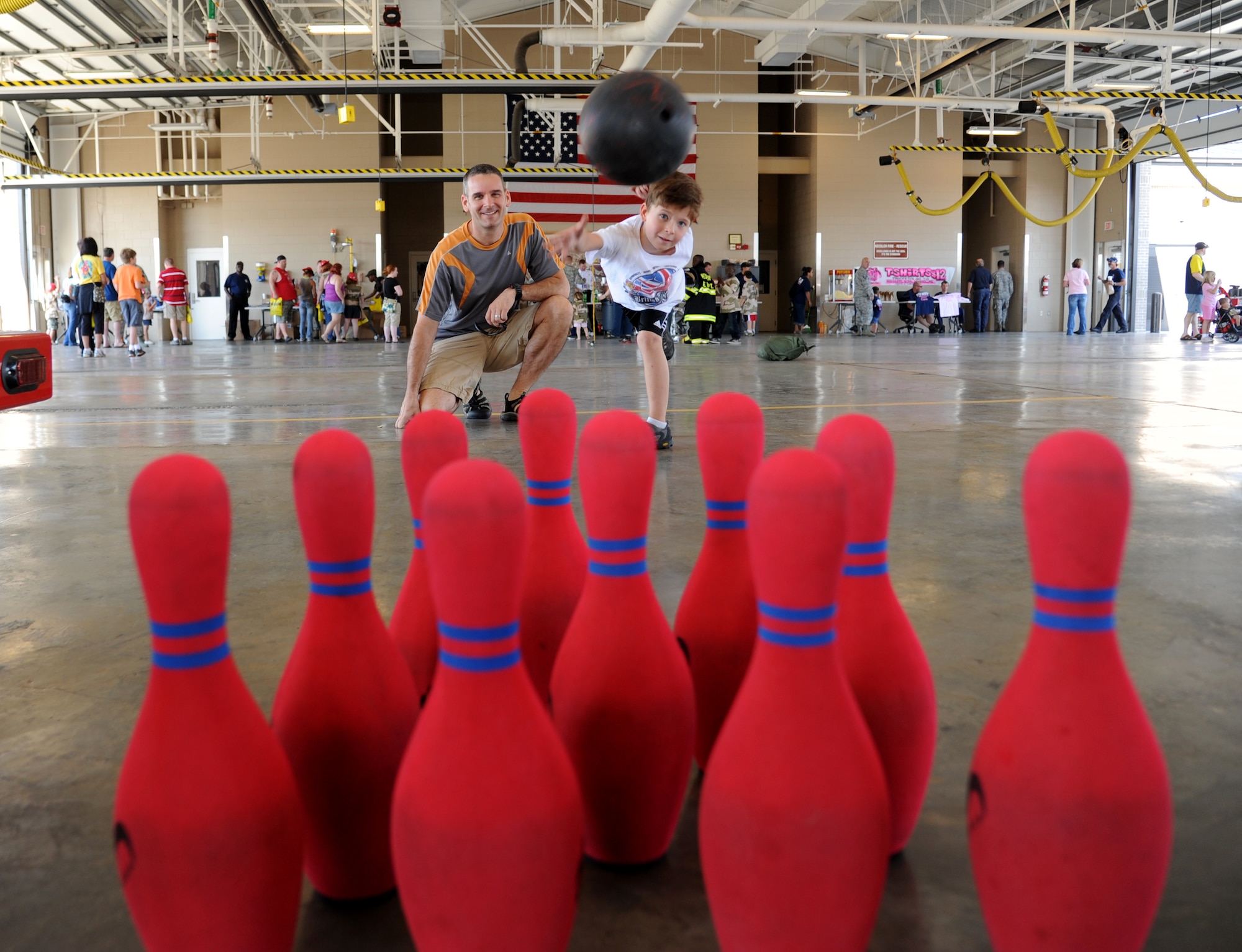 Maj. Matthew Pignataro, 81st Security Forces Squadron commander, watches his son, A.J., 7, toss a rubber bowling ball at bowling pins during the Keesler Fire Department’s open house Oct. 13, 2012, Keesler Air Force Base, Miss.  The event was held on the final day of fire prevention week during which the fire department conducted random fire drills throughout the base, toured various facilities with Sparky the Fire Dog, passed out fire safety handouts and fire hats for children and provided stove and fire extinguisher demonstrations.  A.J.’s mother, Lt. Col. Carolyn Pignataro, 81st Medical Group, is currently deployed to Afghanistan.  (U.S. Air Force photo by Kemberly Groue)