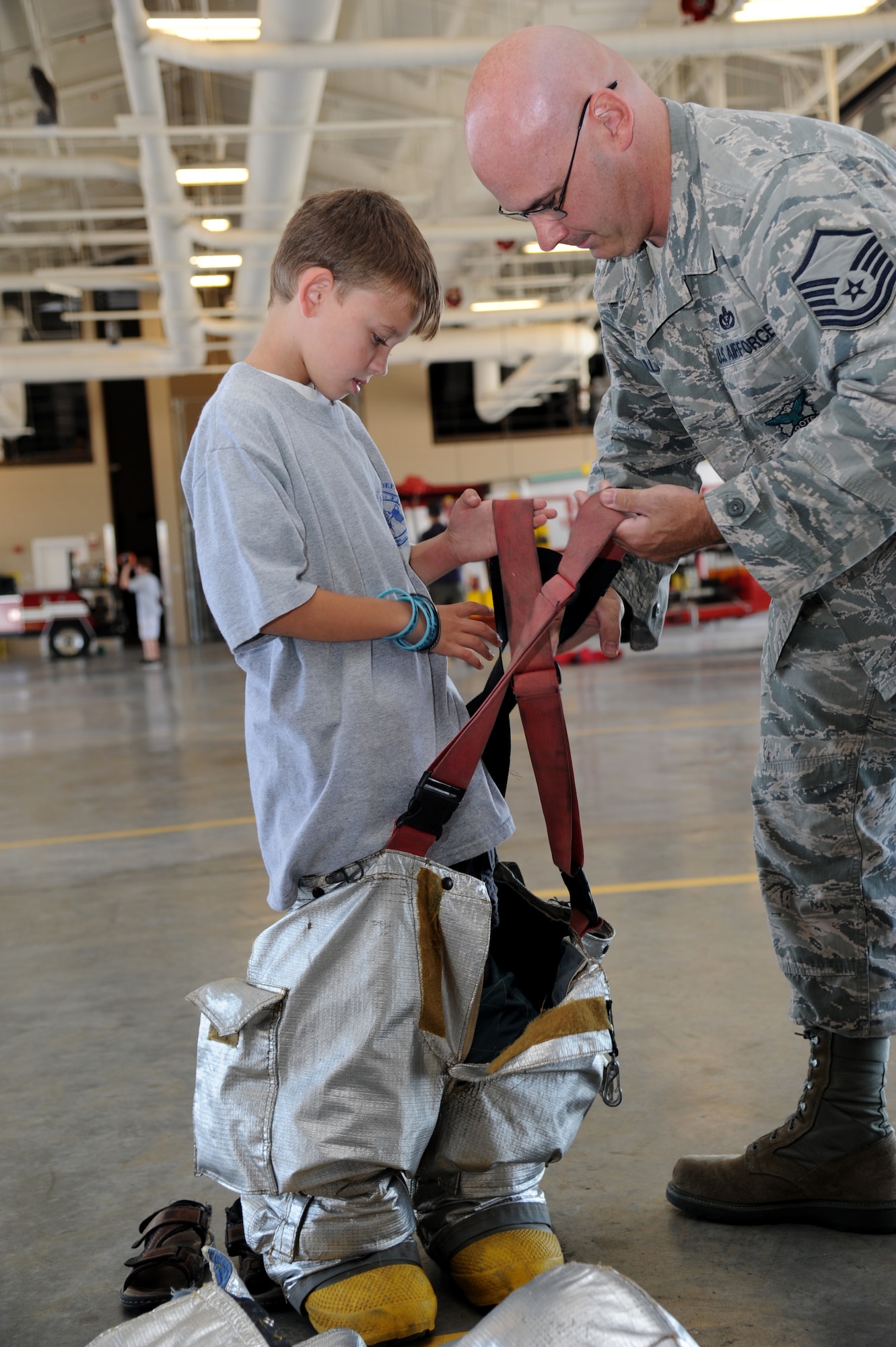 Kaleb Bullard, 8, receives assistance from his dad, Master Sgt. Jerame Bullard, Keesler firefighter, with putting on firefighter gear during the Keesler Fire Department’s open house Oct. 13, 2012, Keesler Air Force Base, Miss.  The event was held on the final day of fire prevention week during which the fire department conducted random fire drills throughout the base, toured various facilities with Sparky the Fire Dog, passed out fire safety handouts and fire hats for children and provided stove and fire extinguisher demonstrations.  (U.S. Air Force photo by Kemberly Groue)