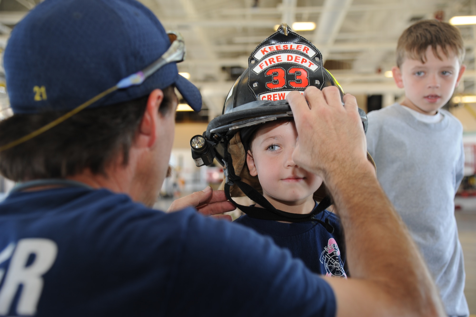 David Cleland, Keesler firefighter, secures a firefighter helmet on Alex Bullard, 4, as his brother, Kaleb, 8, watches during the Keesler Fire Department’s open house Oct. 13, 2012, Keesler Air Force Base, Miss.  Alex and Kaleb’s parents are Master Sgts. Jerame Bullard, Keesler firefighter, and Sarah Bullard, 81st Dental Squadron. The event was held on the final day of fire prevention week during which the fire department conducted random fire drills throughout the base, toured various facilities with Sparky the Fire Dog, passed out fire safety handouts and fire hats for children and provided stove and fire extinguisher demonstrations.  (U.S. Air Force photo by Kemberly Groue)