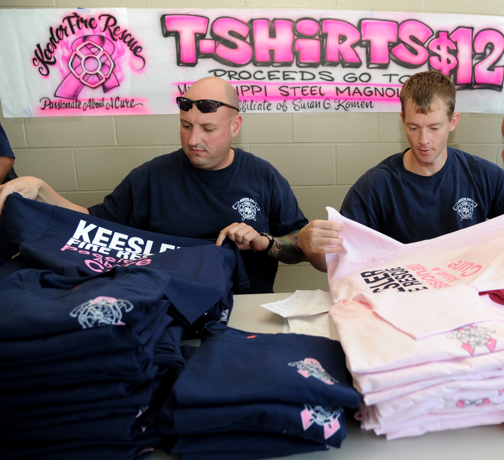 James Tate and Jason Wallace, Keesler firefighters, sort breast cancer awareness T-shirts to sell by the Keesler Fire Department during the department’s open house Oct. 13, 2012, Keesler Air Force Base, Miss.  The event was held on the final day of fire prevention week during which the fire department conducted random fire drills throughout the base, toured various facilities with Sparky the Fire Dog, passed out fire safety handouts and fire hats for children and provided stove and fire extinguisher demonstrations.  (U.S. Air Force photo by Kemberly Groue)