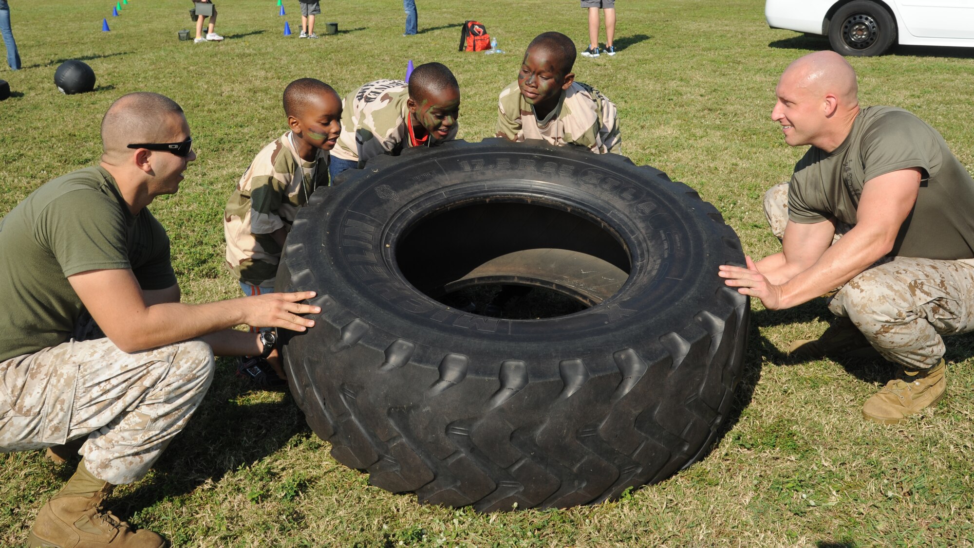 Sgts. Charles Steinruck and Matthew Petitgout, Keesler Marine Detachment, assist Akeem Farquharson, 3, and his brothers, Ardennie Jr., 10, and Kimani, 8, with flipping a large tire during Operation Hero Oct. 13, 2012, at Keesler Air Force Base, Miss.  Operation Hero is presented twice a year to give parents a chance to expose their children to what happens when they leave home for deployments tasking or on temporary duty.  The boys’ parents are Ardennie and Tech. Sgt. Vonetta Farquharson, 81st Logistics Readiness Squadron.  (U.S. Air Force photo by Kemberly Groue)