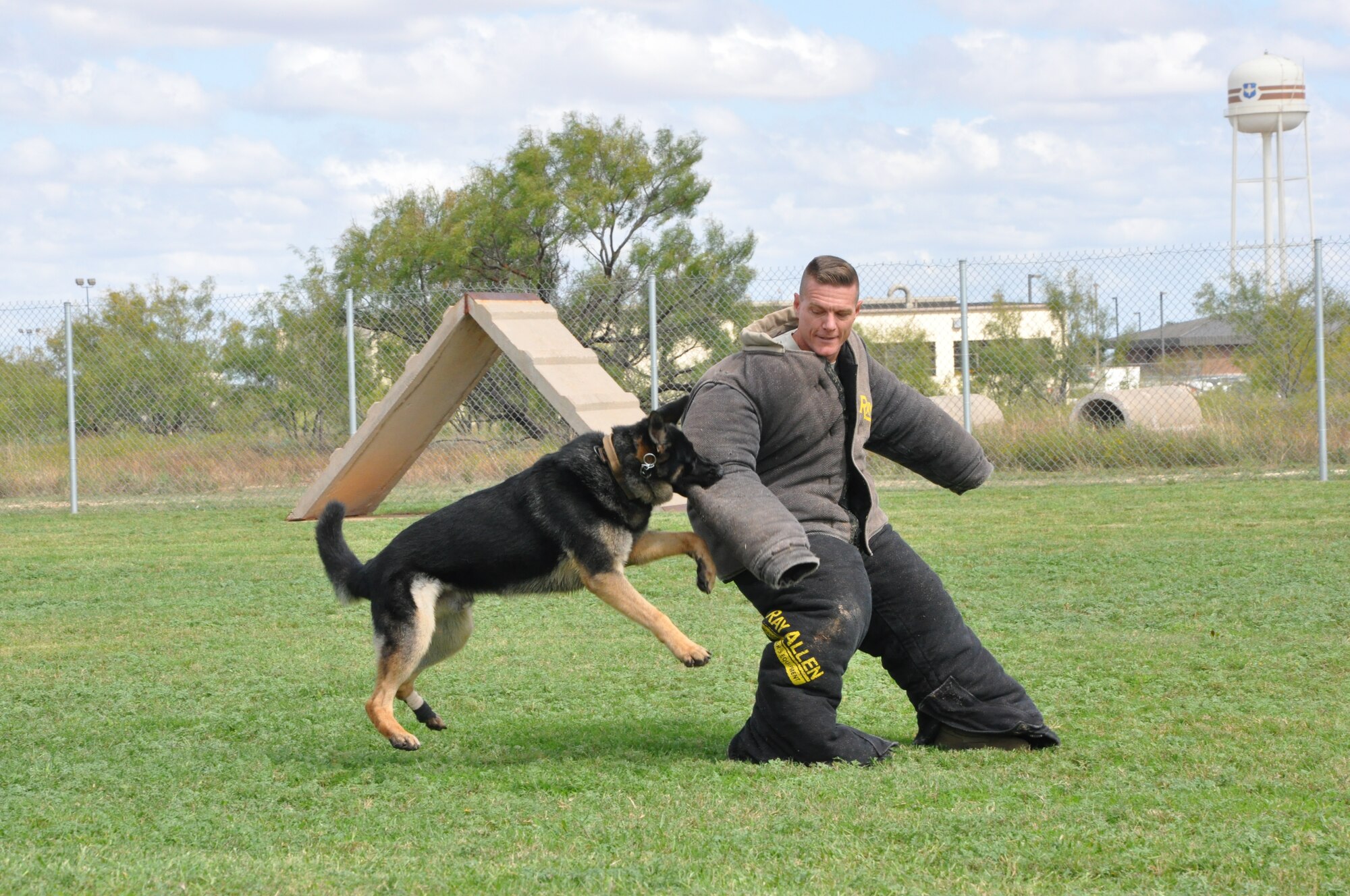 GOODFELLOW AIR FORCE BASE, Texas- Col. Brendan Harris, 17th Training Group commander, sports a protective suit while one of the base Security Forces K-9 unit’s dogs shows his training at the Combined Federal Campaign finale Oct. 12, here. Base leaders volunteered to help out with the finale by dressing in protective wear and allowing, under a controlled environment, the trained dogs to attack and take them down while attendees made contributions to the CFC. (U.S. Air Force photo/ Airman 1st Class Erica Rodriguez)