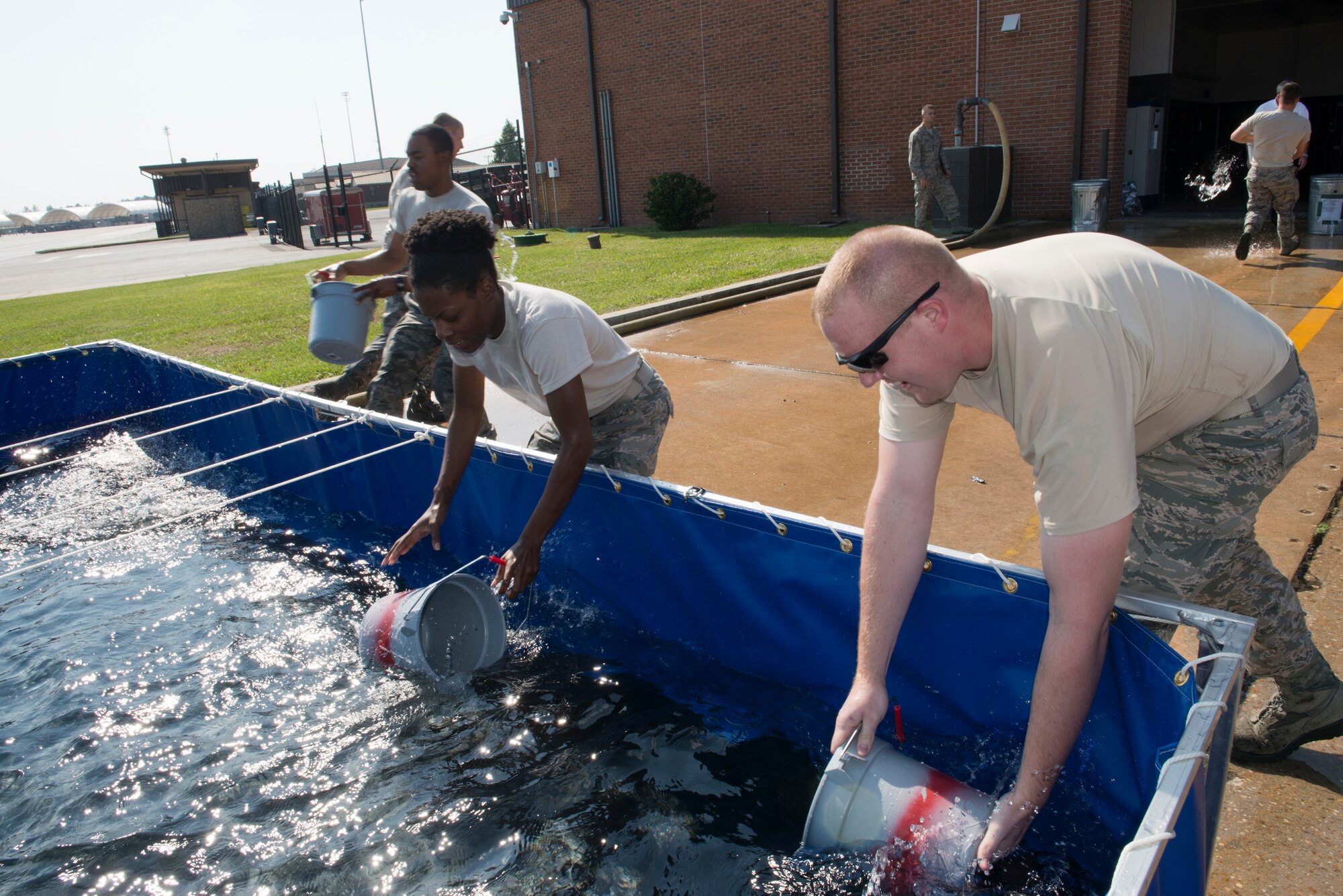 Airmen fill buckets with water during the Firefighter Combat Challenge at Moody Air Force Base, Ga., Oct. 12, 2012. The Airmen used buckets of water to fill aluminum cans, staged 25 feet away. The cumulative time for completing all activities determined the winner. (U.S. Air Force photo by Senior Airman Douglas Ellis/Released)
