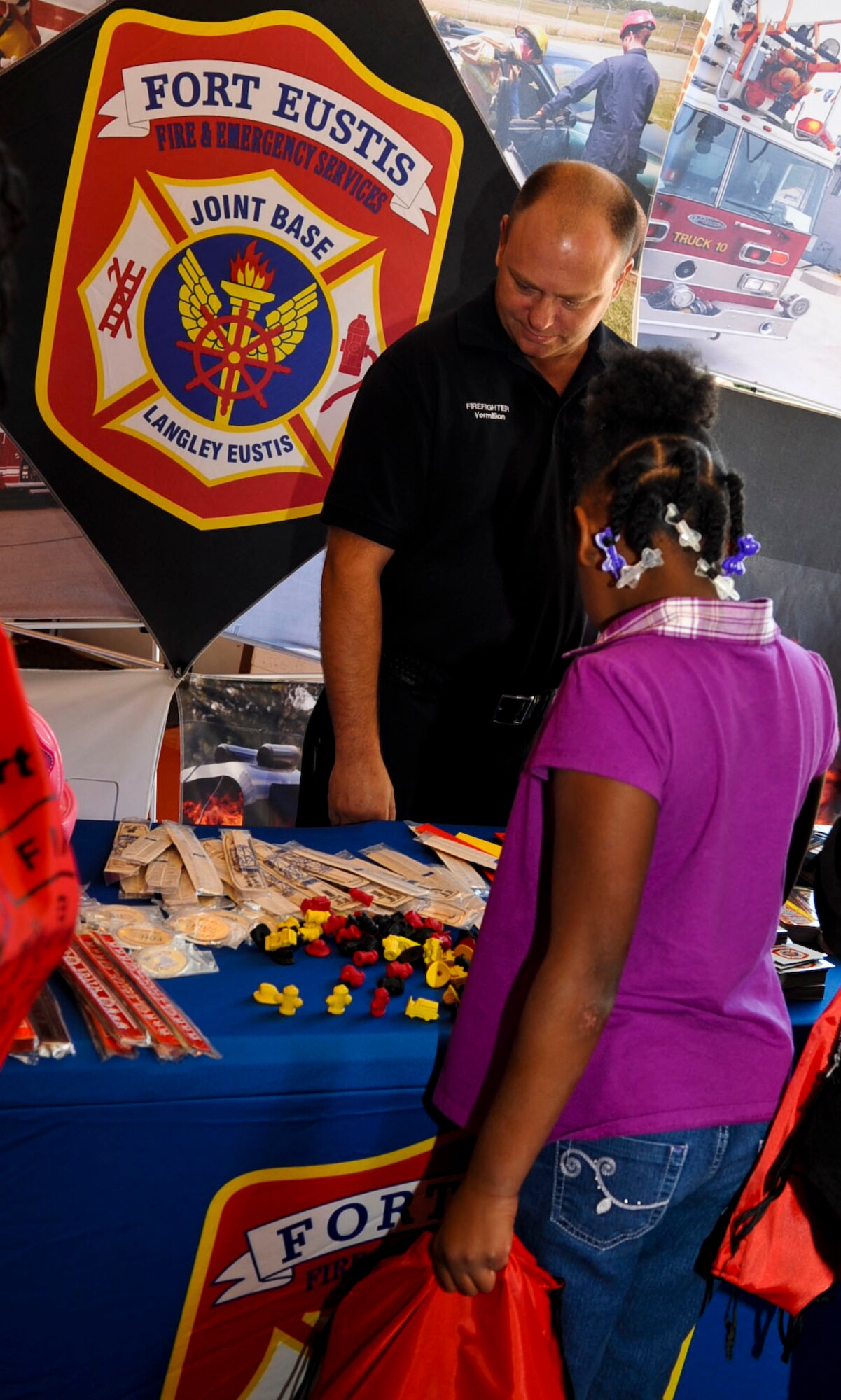 Mel Vermillion, Fort Eustis Fire Department firefighter, shows 7-year-old Tabitha Boyd the items available for her to select from on their give-away table at the fire department open house as part of Fire Prevention Week at Fort Eustis, Va., Oct. 13, 2012. The open house marked the conclusion of a week’s events focused on fire prevention on the post. (U.S. Air Force photo by Staff Sgt. Wesley Farnsworth / Released) 