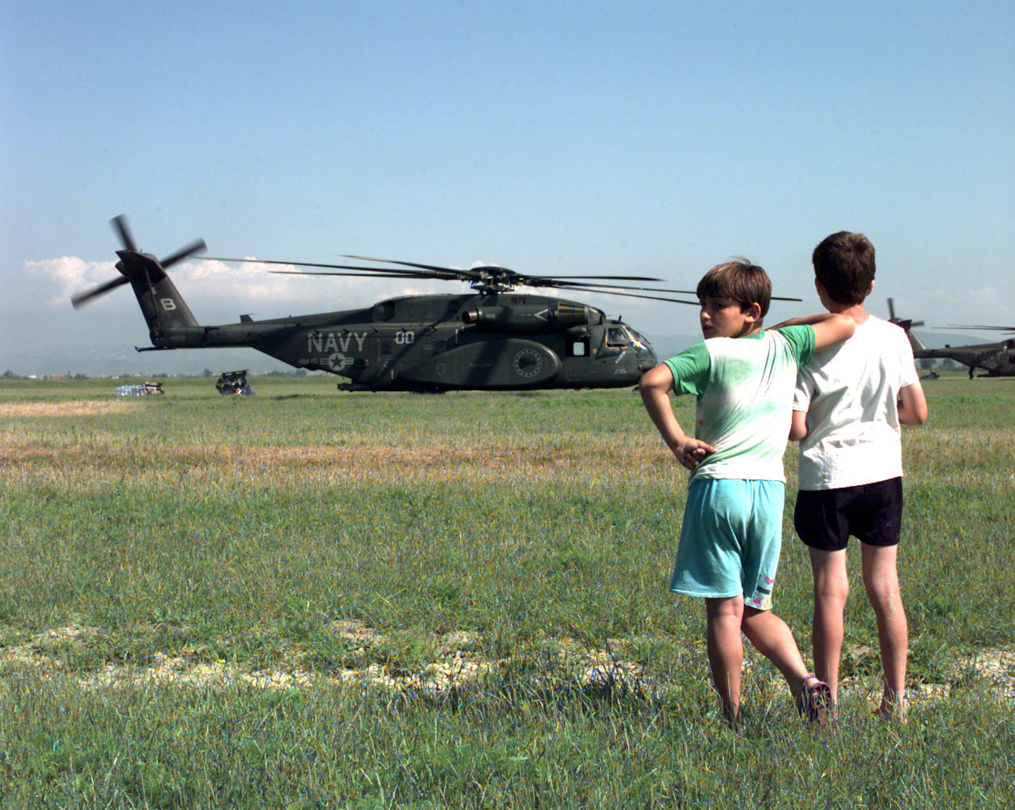 Two refugee children watch as relief supplies are unloaded from U.S. Navy MH-53E Sea Dragon helicopters at Camp Hope near Fier, Albania, on May 13, 1999, during Operation Sustain Hope. Sustain Hope brought in food, water, medicine, relief supplies, and established camps for refugees fleeing from the Former Republic of Yugoslavia. (U.S. Air Force photo by Senior Airman Michelle Leonard)