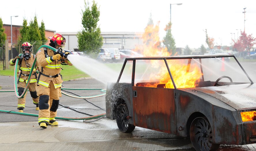 Master Sgt. Matthew Luetkemeyer, front, 100th Civil Engineer Squadron Fire Department, and Crew Manager Lee Spencer, put out a vehicle fire during a demonstration at the fire department’s open house Oct. 12, 2012, at RAF Mildenhall, England. The demonstration was one of several held for Fire Prevention Week. (U.S. Air Force photo by Karen Abeyasekere/Released)