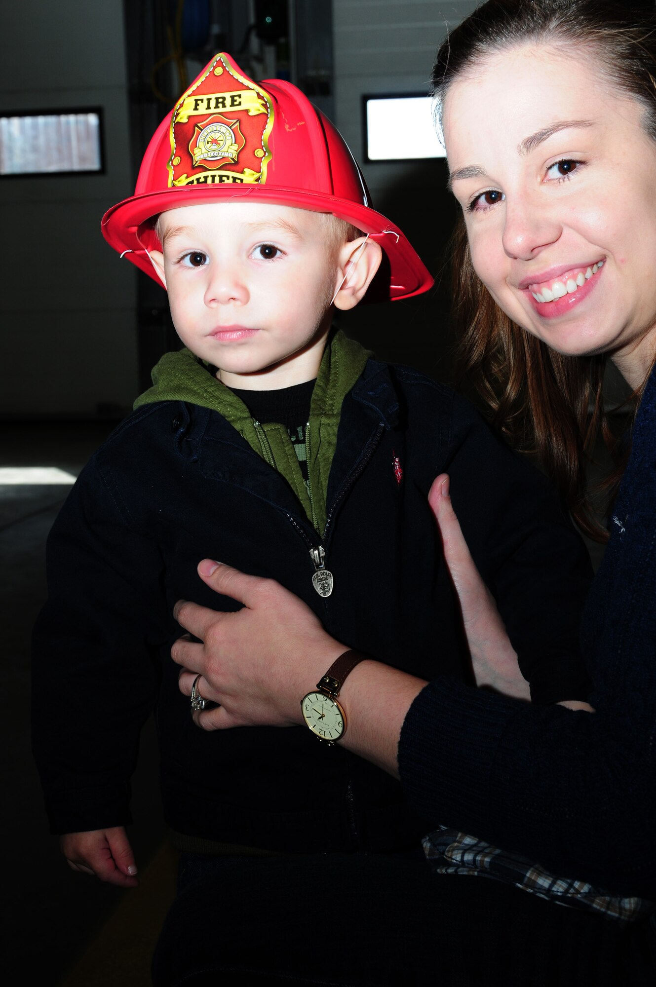 JAC Cranfill, 2, shows off his firefighter’s helmet with mom, Ashley Cranfill, 100th Civil Engineer Squadron spouse, during an open house Oct. 12, 2012, at the RAF Mildenhall Fire Department, England. Firefighters performed demonstrations including a live vehicle fire and the fire prevention trailer, and had bouncy castles and giveaways. The event was one of many during Fire Prevention Week. (U.S. Air Force photo by Karen Abeyasekere/Released)