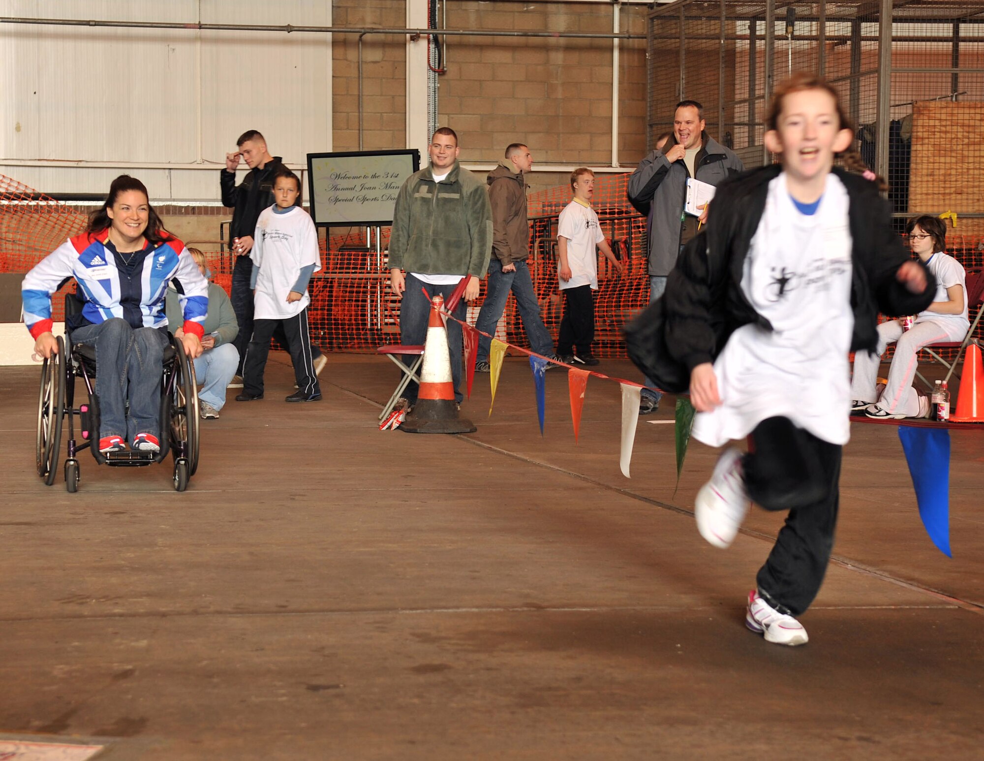 Paralympian Sarah Grady watches as Caitlin McGrane runs ahead of her in the 100-yard run during Joan Mann Special Sports Day Oct. 13, 2012, at RAF Mildenhall, England. Grady and fellow Paralympian Jonathan Adams were among the special guests invited to the base to celebrate the 31st anniversary of the event. (U.S. Air Force photo by Senior Airman Jerilyn Quintanilla/Released)