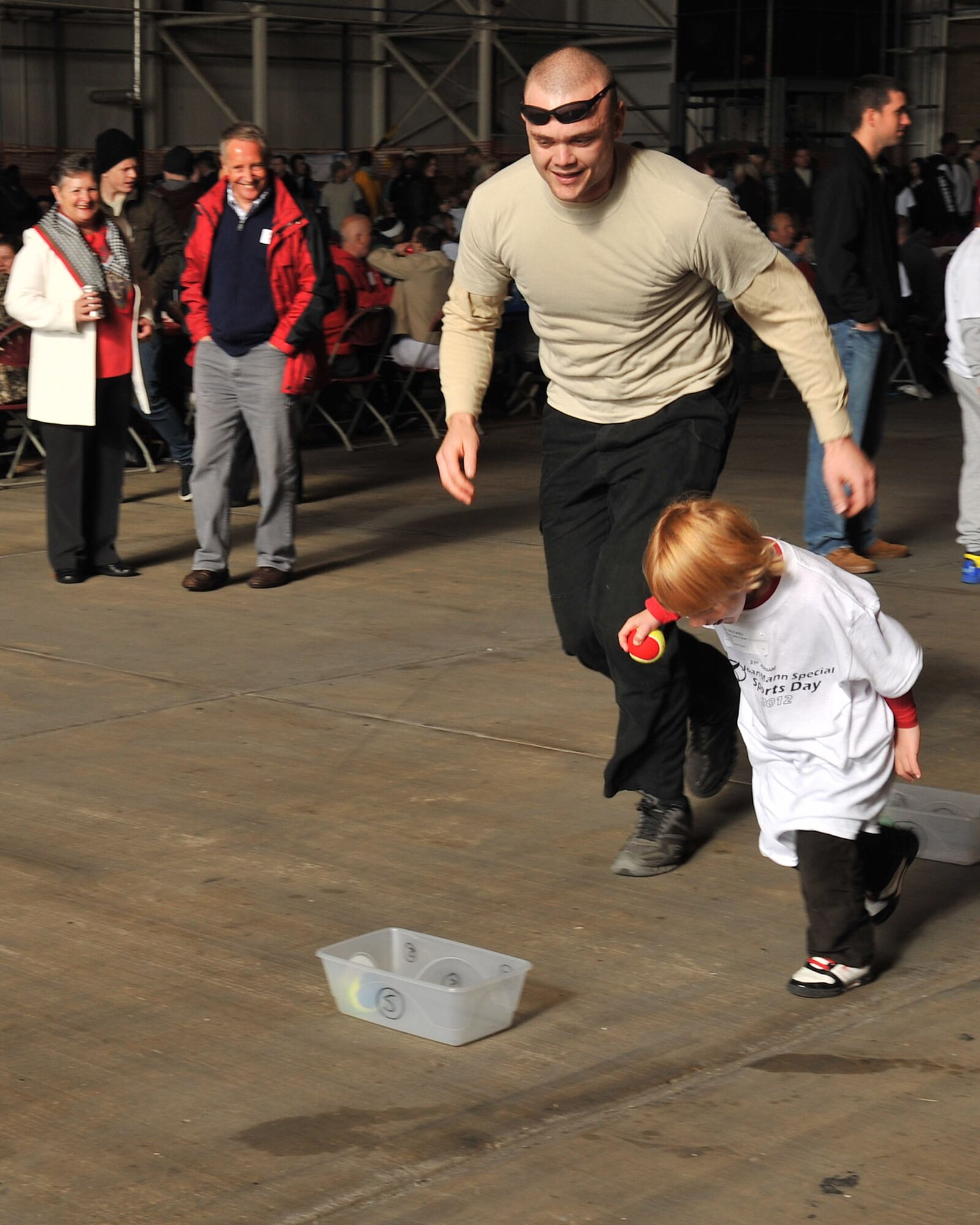 Staff Sgt. Christopher Daniels, Defense Courier Service, chases after Jacob McCarthy, 6, during the tennis bounce game during Joan Mann Special Sports Day Oct. 13, 2012, at RAF Mildenhall, England. McCarthy was one of more than 200 special athletes welcomed to the base for a day of games, food and dancing. (U.S. Air Force photo by Senior Airman Jerilyn Quintanilla/Released)