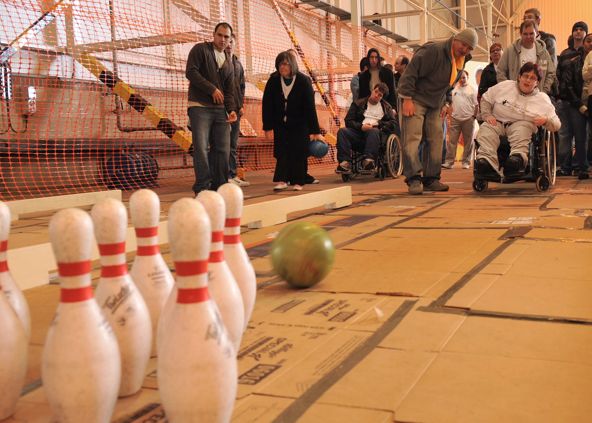 Tech. Sgt. Rexangelo Lualhati, wearing hat, 100th Air Refueling Wing Inspector General’s office, and Emma Babey watch as her bowling ball makes its way to the pins during Joan Mann Special Sports Day Oct. 13, 2012, at RAF Mildenhall, England. The base hosted more than 200 special athletes from the local area for a day of games, food and dancing. (U.S. Air Force photo by Senior Airman Jerilyn Quintanilla/Released)