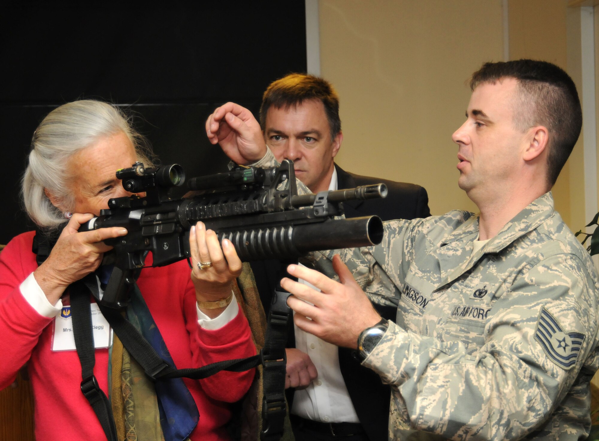 Jennie Clegg, wife of Duncan Clegg, High Sheriff of Gloucestershire, looks through a scope on an M4 carbine with the assistance of Tech. Sgt. Erik Ellingson, 48th Security Forces Squadron NCO-in charge of training, during a tour Oct. 12, 2012, at RAF Feltwell, England. The high sheriffs of several counties, their spouses and several other distinguished guests visited RAF Mildenhall, RAF Lakenheath and RAF Feltwell for a community relations tour hosted by U.S. Air Forces in Europe - United Kingdom. (U.S. Air Force photo by Tech. Sgt. Neal X. Joiner/Released) 