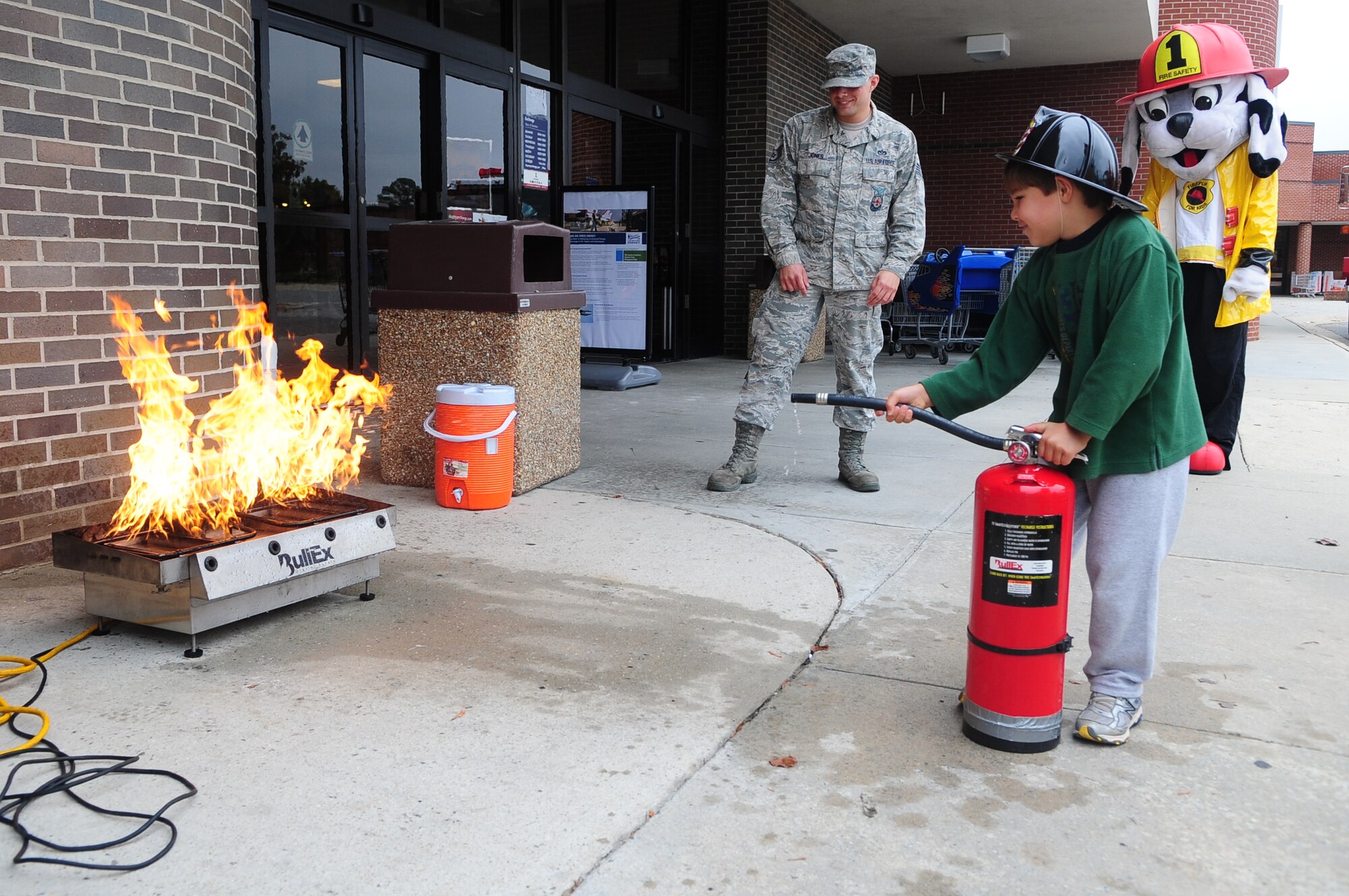 Caleb Ramirez, 6, puts out a fire during a Fire Prevention Week demonstration on Seymour Johnson Air Force Base, N.C., Oct. 9, 2012. Airmen assigned to the 4th Civil Engineer Squadron Fire Department taught children how to use a fire extinguisher for small kitchen fires. Caleb is the son of U.S. Air Force Capt. David Ramirez, 916th Operations Support Squadron intelligence analyst. (U.S. Air Force photo/Airman 1st Class Aubrey White/Released)