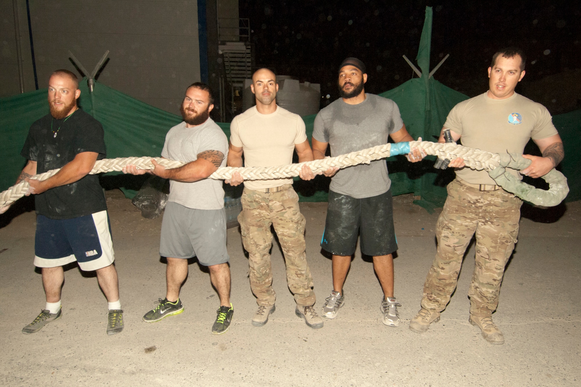 U.S. Air Force Airmen and civilians hold the tug-of-war rope after a winning a tug-of-war contest at Bagram Airfield, Afghanistan, Oct. 13, 2012. The tug-of-war was a “two out of three” contest with two five-man teams competing. “Team America” came out on top by winning the first two matchups. The team included Airmen from the 455th Expeditionary Security Forces Squadron, Air Force Office of Special Investigations, and contractors. (U.S. Air Force photo/SSgt Jeff Nevison)