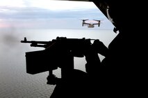 Chief Warrant Officer 2 Daniel E. Fuson, Marine Medium Tiltrotor Squadron 162 avionics officer and aerial observer, fires the tail-mounted M240D at a target in the water, Oct. 3. The Golden Eagles learned how to use a tail gun to defend Ospreys from ground threats in a training flight. 