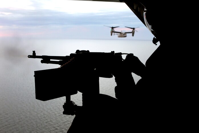 Chief Warrant Officer 2 Daniel E. Fuson, Marine Medium Tiltrotor Squadron 162 avionics officer and aerial observer, fires the tail-mounted M240D at a target in the water, Oct. 3. The Golden Eagles learned how to use a tail gun to defend Ospreys from ground threats in a training flight. 