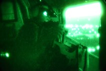 A crew chief from Marine Heavy Helicopter Squadron 461 looks out the window of his CH-53E during a simulated combat flight mission at night. The training also allowed the Marines to earn their division leader qualificaitons, Oct. 3.