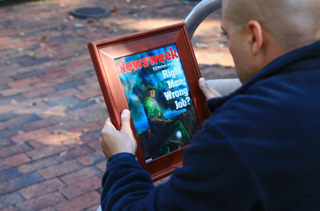 First Sgt. Laureano Perez, the first sergeant of Headquarters Company, Combat Logistics Battalion 6, 2nd Marine Logistics Group, examines a magazine cover photo of Richard L. Ray, a retired gunnery sergeant who spoke with Marines from CLB-6, at the Beirut Memorial near Camp Lejeune, N.C., Oct. 11, 2012. Ray talked to the Marines about what it was like to be in Lebanon after the 1983 bombing of the Marine barracks in Beirut. 