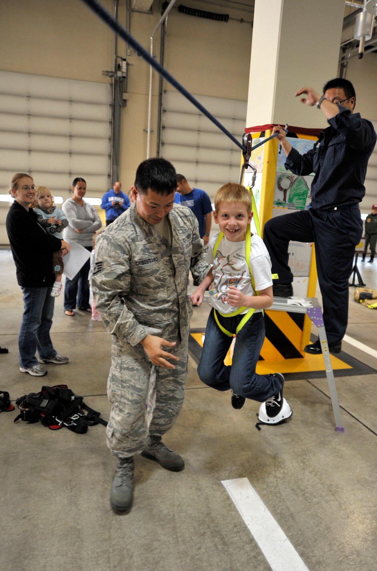 U.S. Air Force Staff Sgt. John-John Crisostomo, left, 35th Civil Engineer Squadron firefighter, pushes the son of Staff Sgt. Nathan Lipscomb, 35th Fighter Wing Public Affairs photographer, across a zip line during the Fire Prevention Week Open House at Misawa Air Base, Japan, Oct. 13, 2012. The open house gave children from base a glimpse into the life of a firefighter as they rolled hoses, crossed zip-lines, suited-up in protective gear and tried their hand at putting out a simulated fire. (U.S. Air Force photo by Staff Sgt. Nathan Lipscomb)