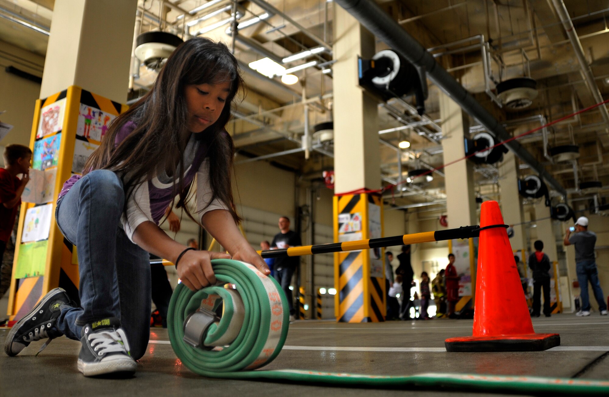 The daughter of Tech. Sgt. Aaron Farrow, 35th Civil Engineer Squadron firefighter, rolls a hose during the Fire Prevention Week Open House at Misawa Air Base, Japan, Oct. 13, 2012. The event gave firefighters the opportunity to connect with the community as they taught fires prevention techniques. (U.S. Air Force photo by Staff Sgt. Nathan Lipscomb)   