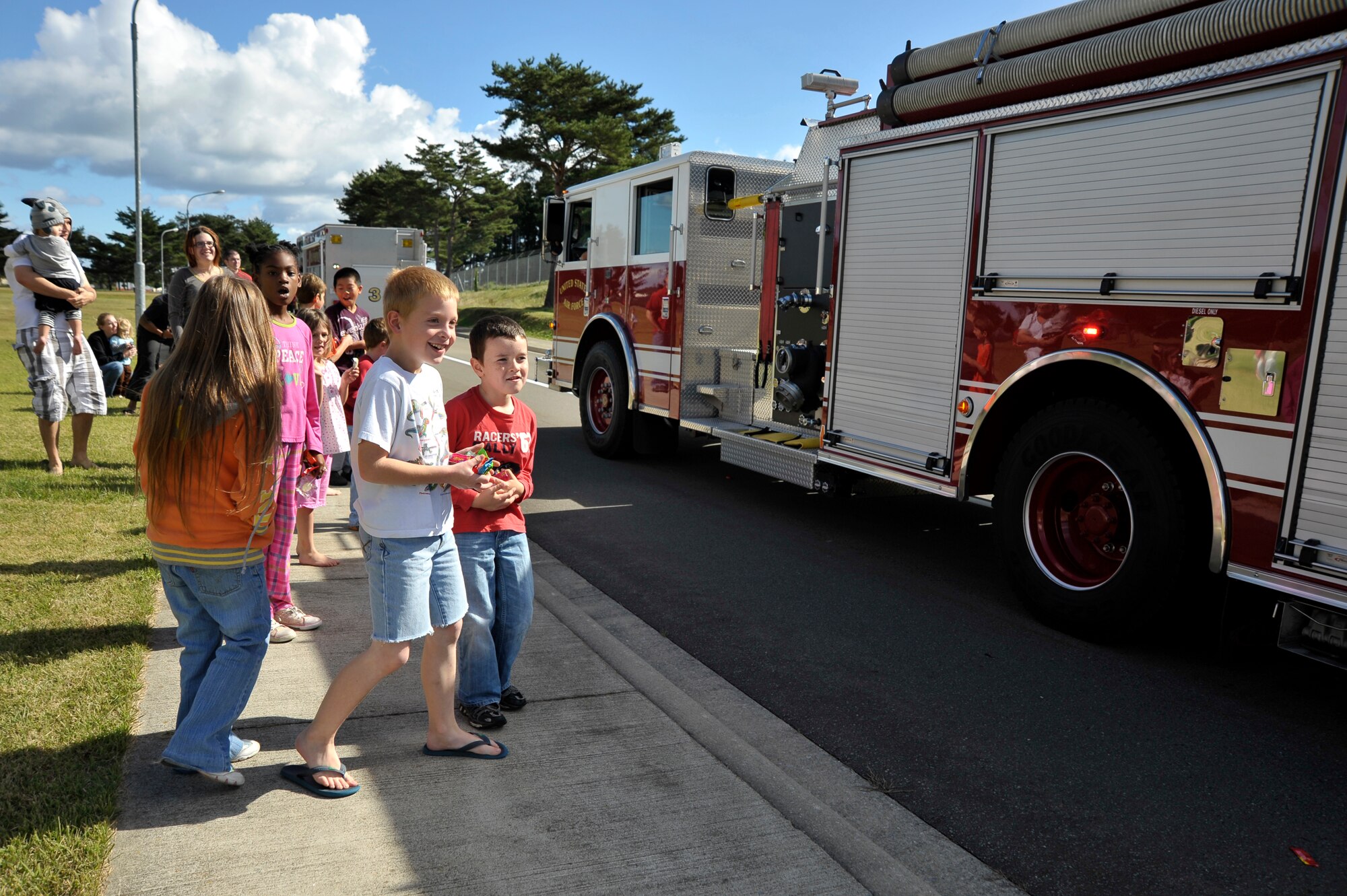 Children line the streets as fire trucks pass by with lights flashing and sirens blaring during the Fire Prevention Week Parade at Misawa Air Base, Japan, Oct. 13, 2012. The parade started the last day of Fire Prevention Week and was followed by an open house at Fire Station 1. (U.S. Air Force photo by Staff Sgt. Nathan Lipscomb)
