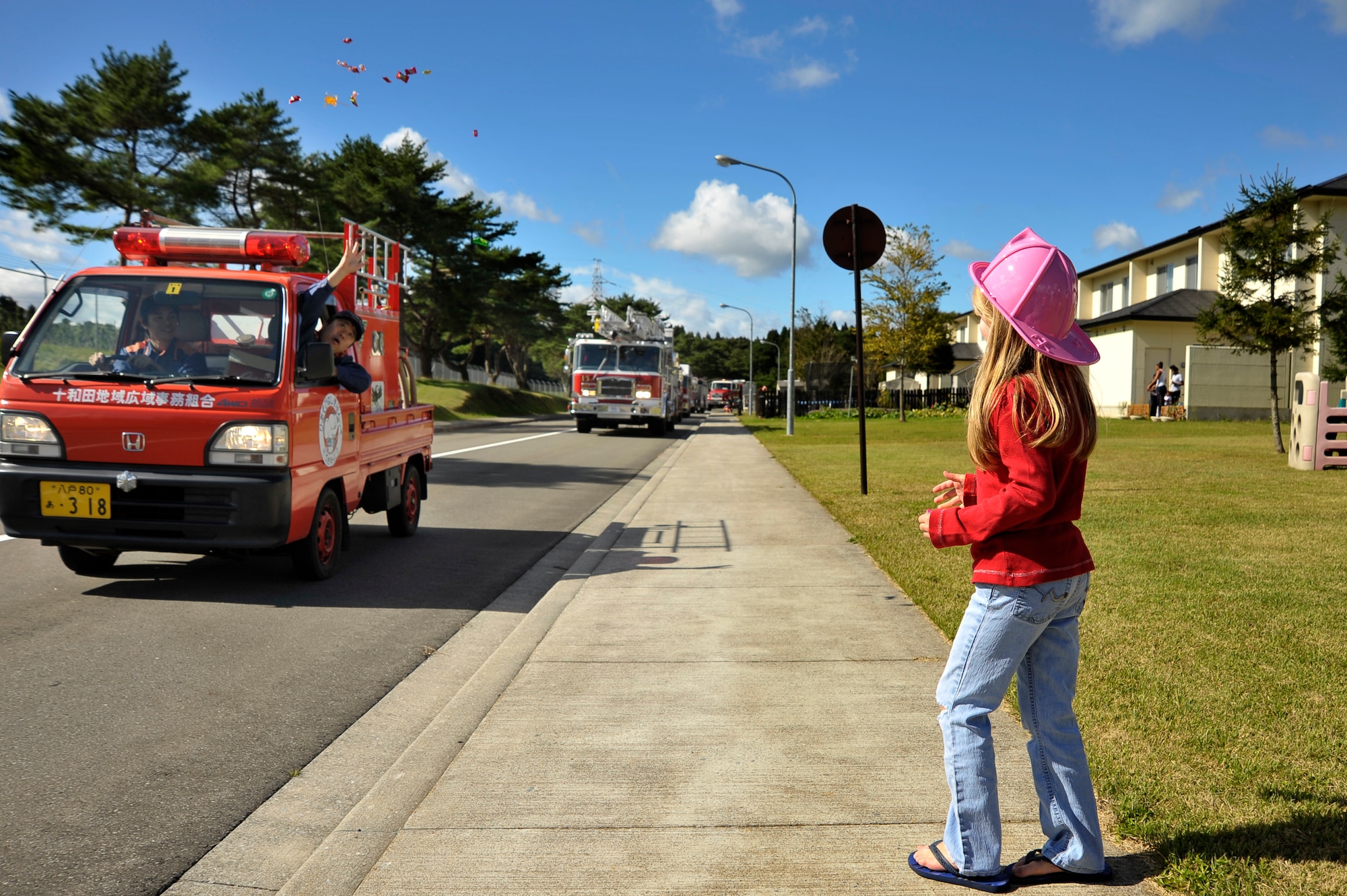 A firefighter from Towada City throws candy to a child during the Fire Prevention Week Parade at Misawa Air Base, Japan, Oct. 13, 2012. The parade made its way around base housing areas showcasing the different fire trucks used by Misawa Air Base, Misawa City and Towada City. (U.S. Air Force photo by Staff Sgt. Nathan Lipscomb)