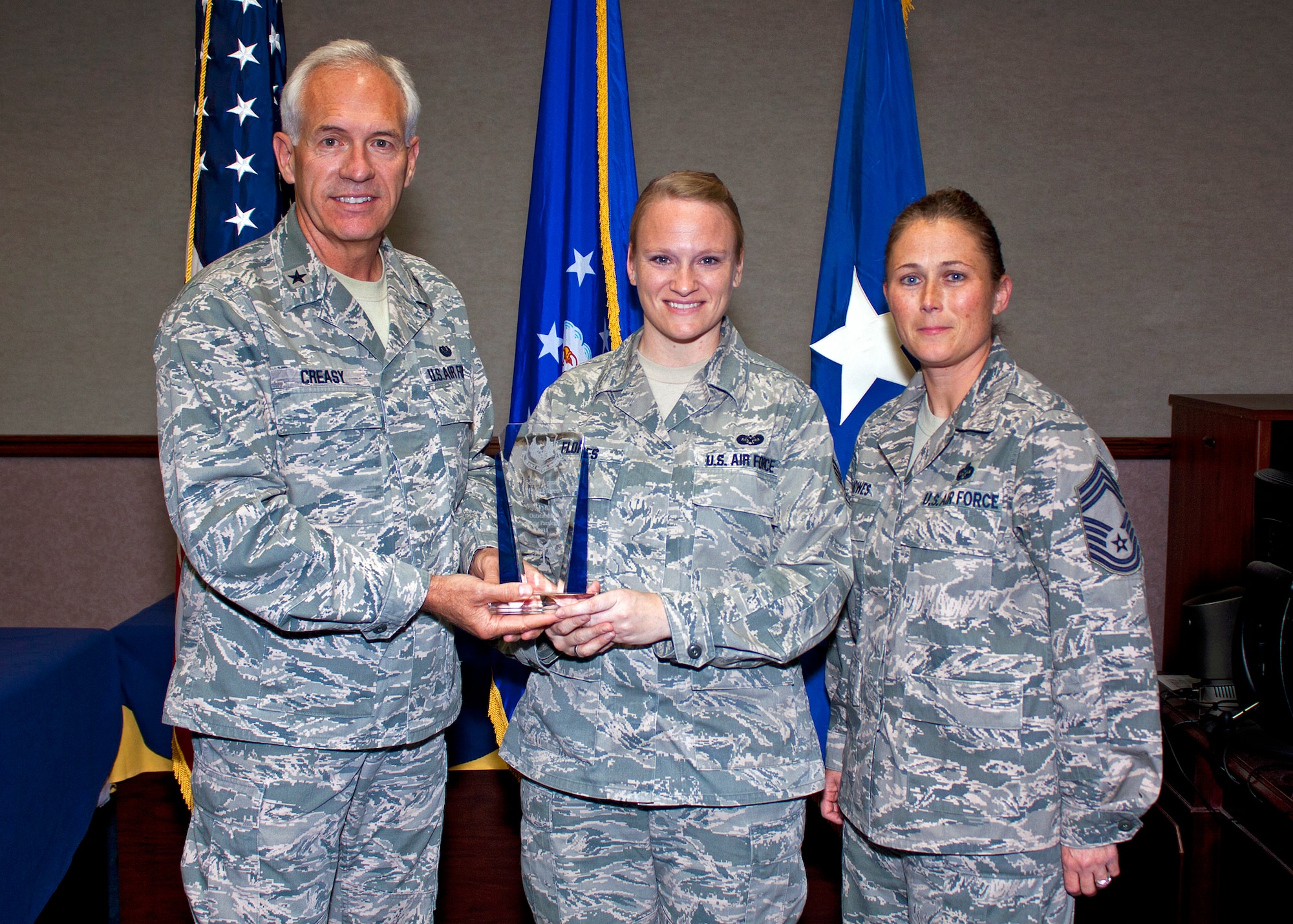 Brig. Gen. Dwight Creasy, AFMC Staff Judge Advocate, and Chief Master Sgt. Sherry Bowes, command paralegal manager for AFMC, present Staff Sgt. Misty Flores (center), 412th TW Judge Advocate noncommissioned officer-in-charge of the Military Justice section, with the 2011 AFMC Paralegal of the Year award at the Edwards courthouse Oct. 3, 2012. (U.S. Air Force photo by MSgt. John McGee)