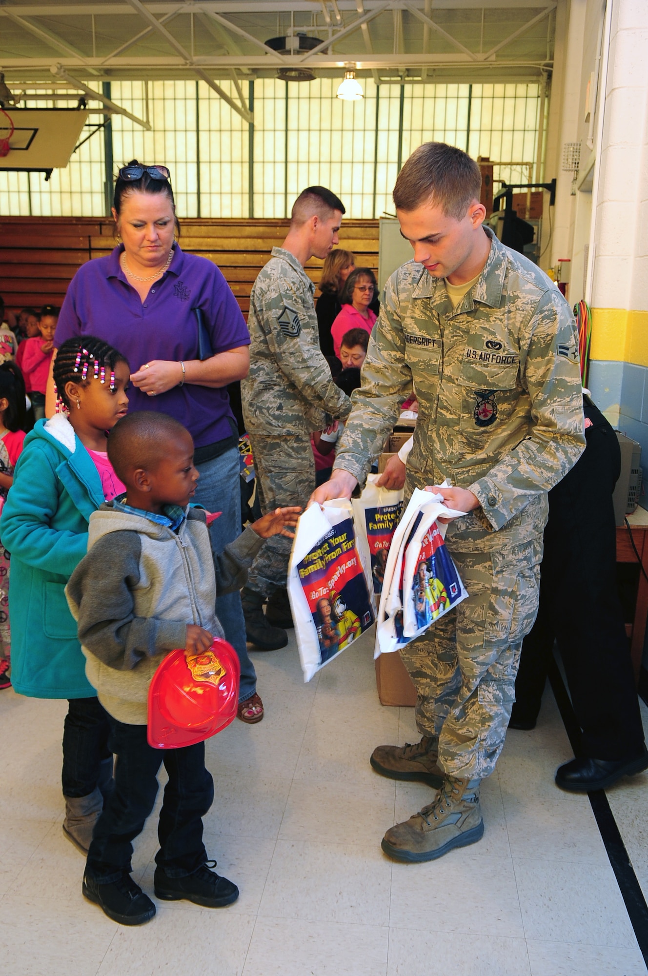 U.S. Air Force Airman 1st Class Benton Vandergrift, 4th Civil Engineer Squadron firefighter, hands out Fire Prevention Week goody bags to children at Meadow Lane Elementary School in Goldsboro, N.C., Oct. 12, 2012. Airmen taught the children fire prevention tips through singing, dancing and a puppet show. (U.S. Air Force photo/Airman 1st Class Aubrey White/Released)