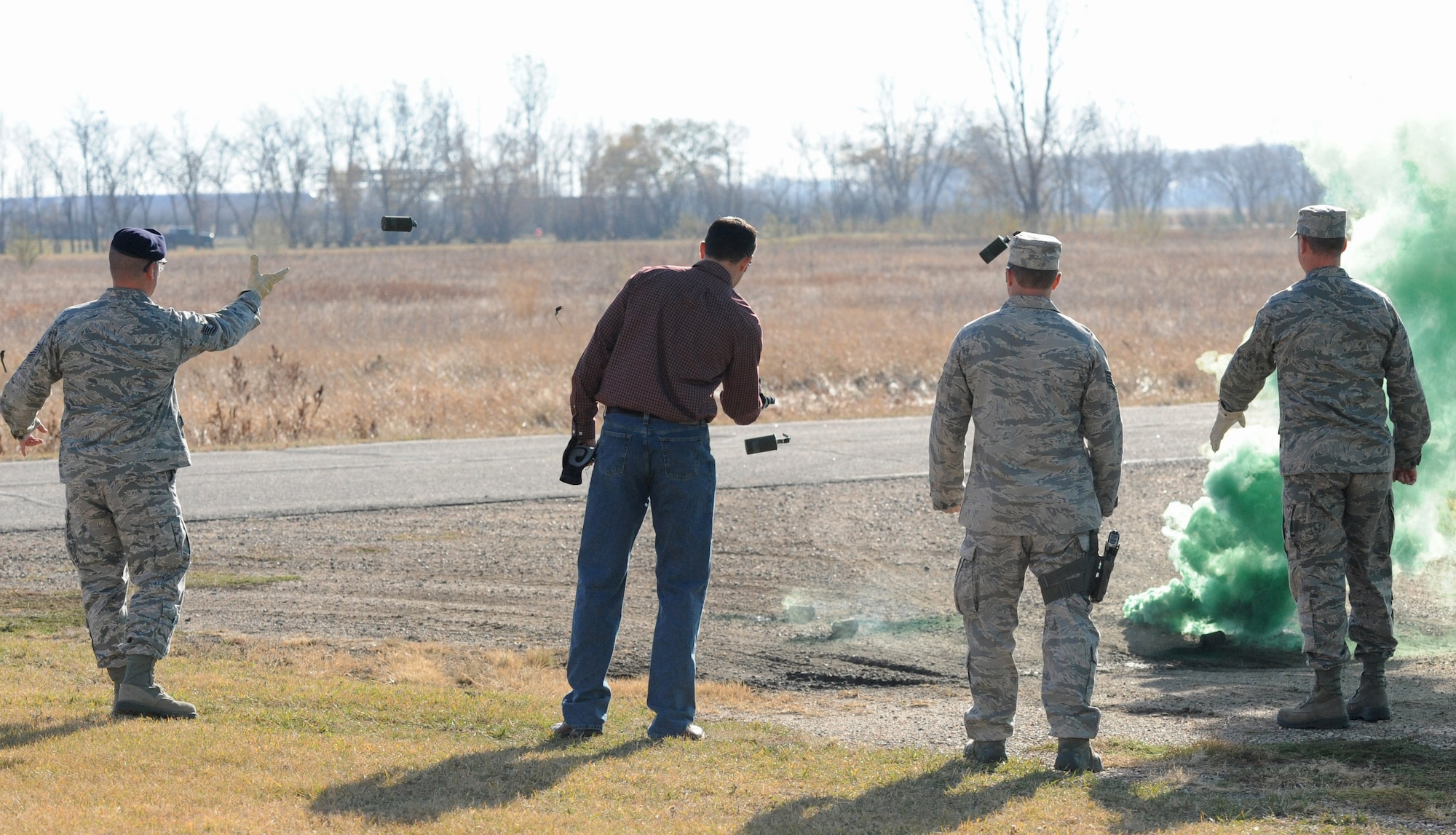 Exercise Evaluation Team members toss M-18 smoke grenades during qualification training Oct. 16, 2012, on Grand Forks Air Force Base, N.D. Smoke grenade and ground burst simulator training was provided to EET members in preparation for an upcoming Readiness Inspection scheduled for May of 2013. (U.S. Air Force photo/Airman 1st Class Derek VanHorn)