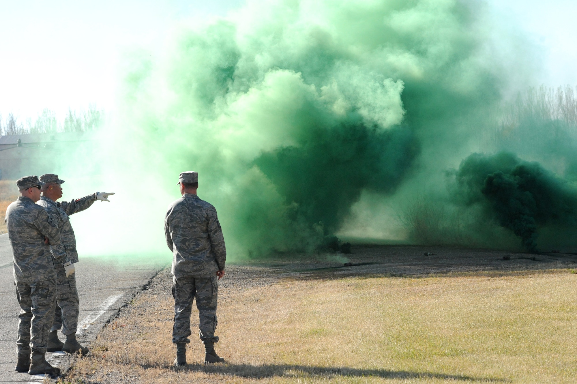 Exercise Evaluation Team members look on after throwing M-18 smoke grenades during qualification training Oct. 16, 2012, on Grand Forks Air Force Base, N.D. Smoke grenade and ground burst simulator training was provided to Emergency Exercise Team members in preparation for an upcoming Readiness Inspection scheduled for May of 2013. (U.S. Air Force photo/Airman 1st Class Derek VanHorn)