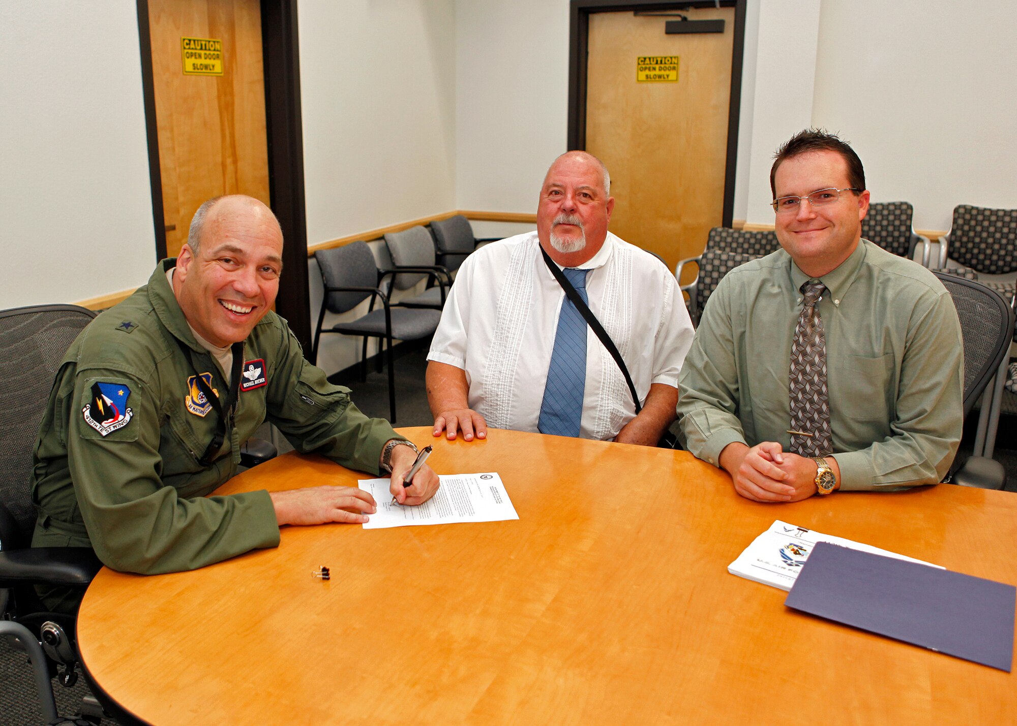 Brig. Gen. Michael T. Brewer, 412th Test Wing commander (far left), signs this year's Energy Action Month Proclamation Oct. 12. The proclamation and energy conservation actions that Edwards will implement this fall and winter were written and planned by Jack Frazier, 412th Civil Engineering Division, Resource Efficiency manager (middle) and Gerald Boetsch, 412th CE, Asset Optimization. (U.S. Air Force photo by Jet Fabara)