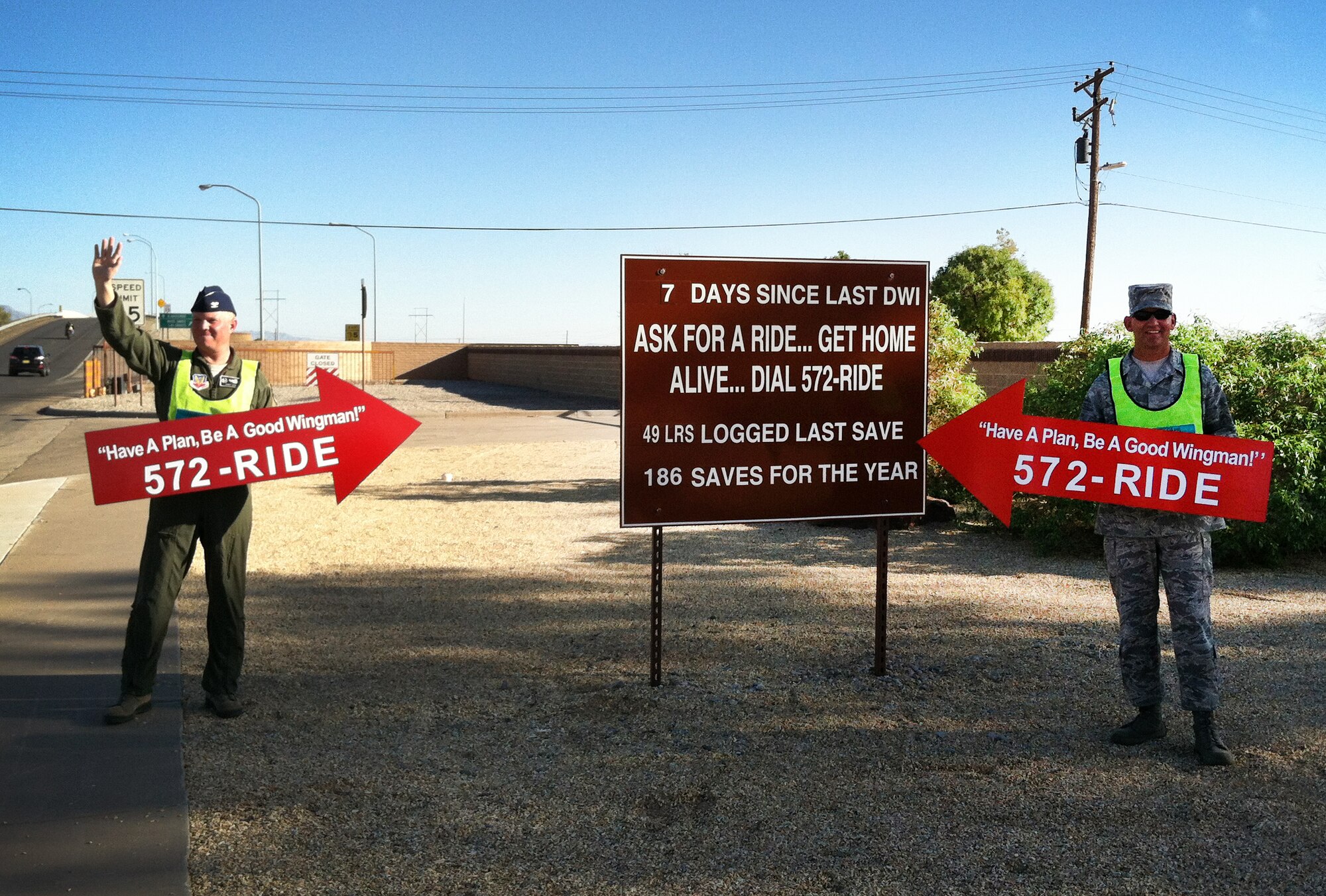 49th Wing commander, Col. Andrew Croft, and Command Chief Master Sgt. James Patrie advertise 572-RIDE outside the gate at Holloman Air Force Base, N.M., Oct. 5 prior to an extended holiday weekend. Any Team Holloman member may anonymously call 572-RIDE with no questions asked as an alternative to driving while intoxicated. (U.S. Air Force photo by 1st Lt. Stephanie Schonberger/Released)