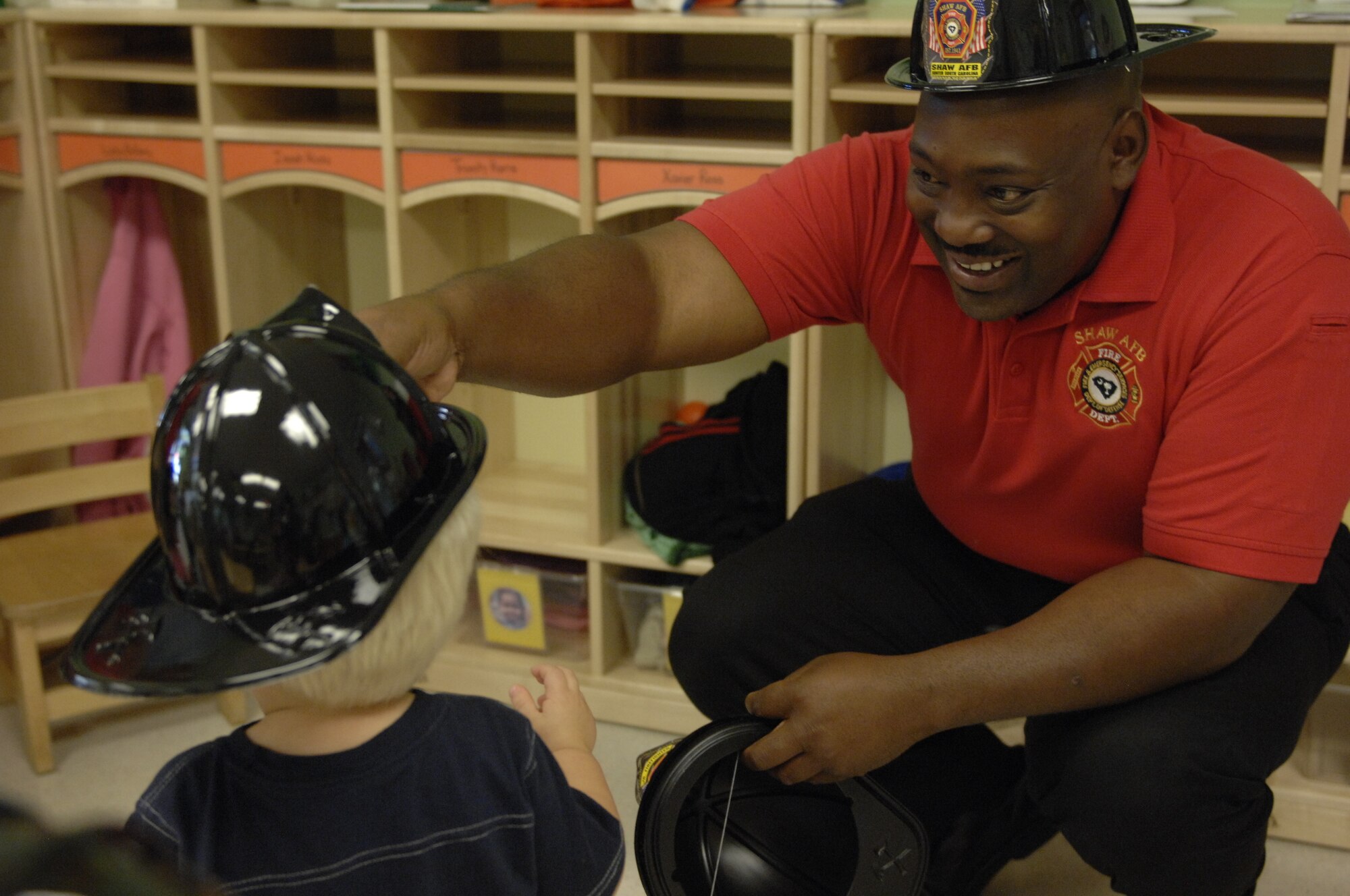 Cornelius Berry, 20th Civil Engineer Squadron fire inspector, gives fire hats to children at the Child Development Center during Fire Prevention Week at Shaw Air Force Base, S.C., Oct. 12, 2012. He was accompanied by Sparky the Fire Dog and they toured the CDC, visiting all of the classrooms. (U.S. Air Force photos by Airman 1st Class Krystal M. Jeffers/Released)