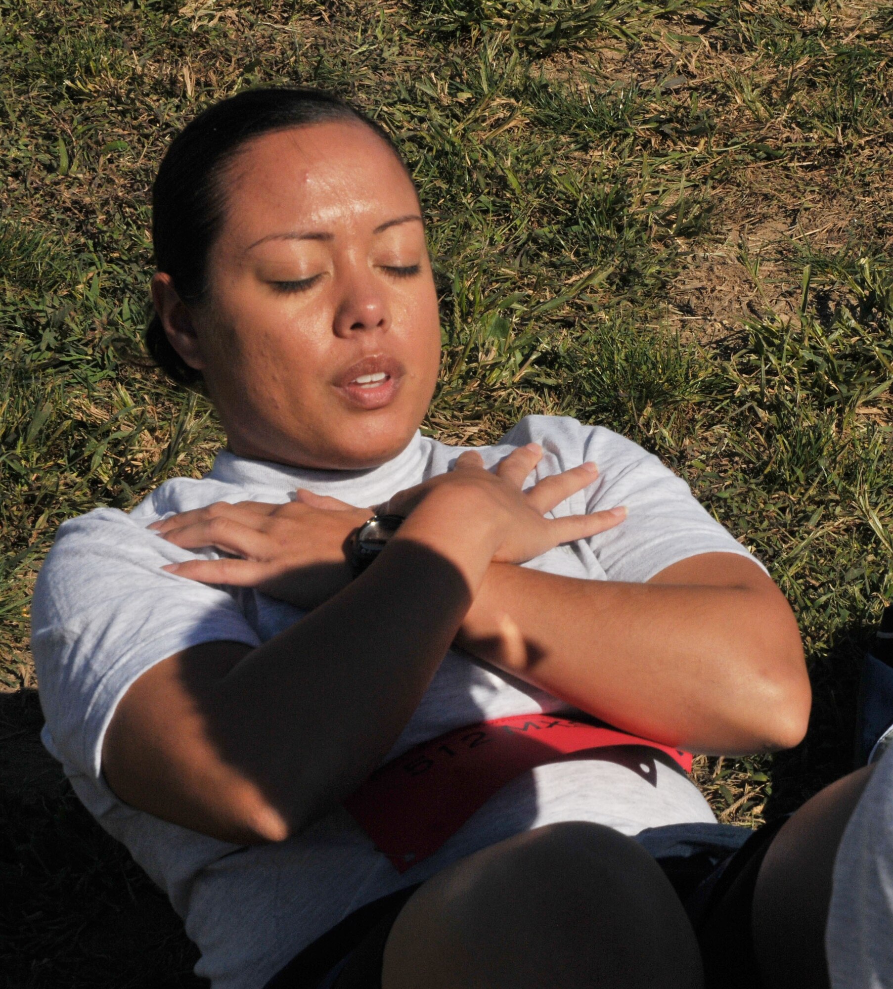 Airman 1st Class Marylynn Morales, a 512th Maintenance Squadron aerospace propulsion mechanic, completes a sit-up while shielding her eyes from the sun at the Ultimate Fitness Challenge Oct. 13, 2012, at the track on Dover Air Force Base, Del. Morales went on to run in the relay race with other members of her squadron. (U.S. Air Force photo by Senior Airman Joe Yanik)
