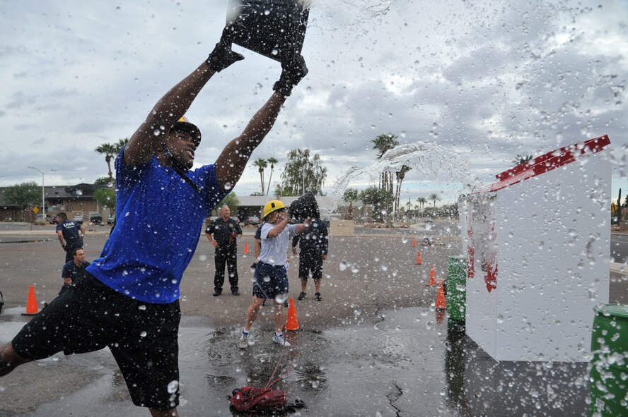 Staff Sgt. Jose Hoskins, 56th Security Forces Squadron desk sergeant, tosses water on the roof of a simulated house during the Bucket Brigade obstacle, the last obstacle of the 2012 Firefighter’s Muster, Oct. 12 at Luke Air Force Base, Ariz. The objective was to fill a barrel with water by transporting water in buckets from the water source and throwing the water onto the roof so the water will run-off from the gutter and into the barrel. Time stops when the barrel overflows. (U.S. Air Force photo by Senior Airman Sandra Welch)