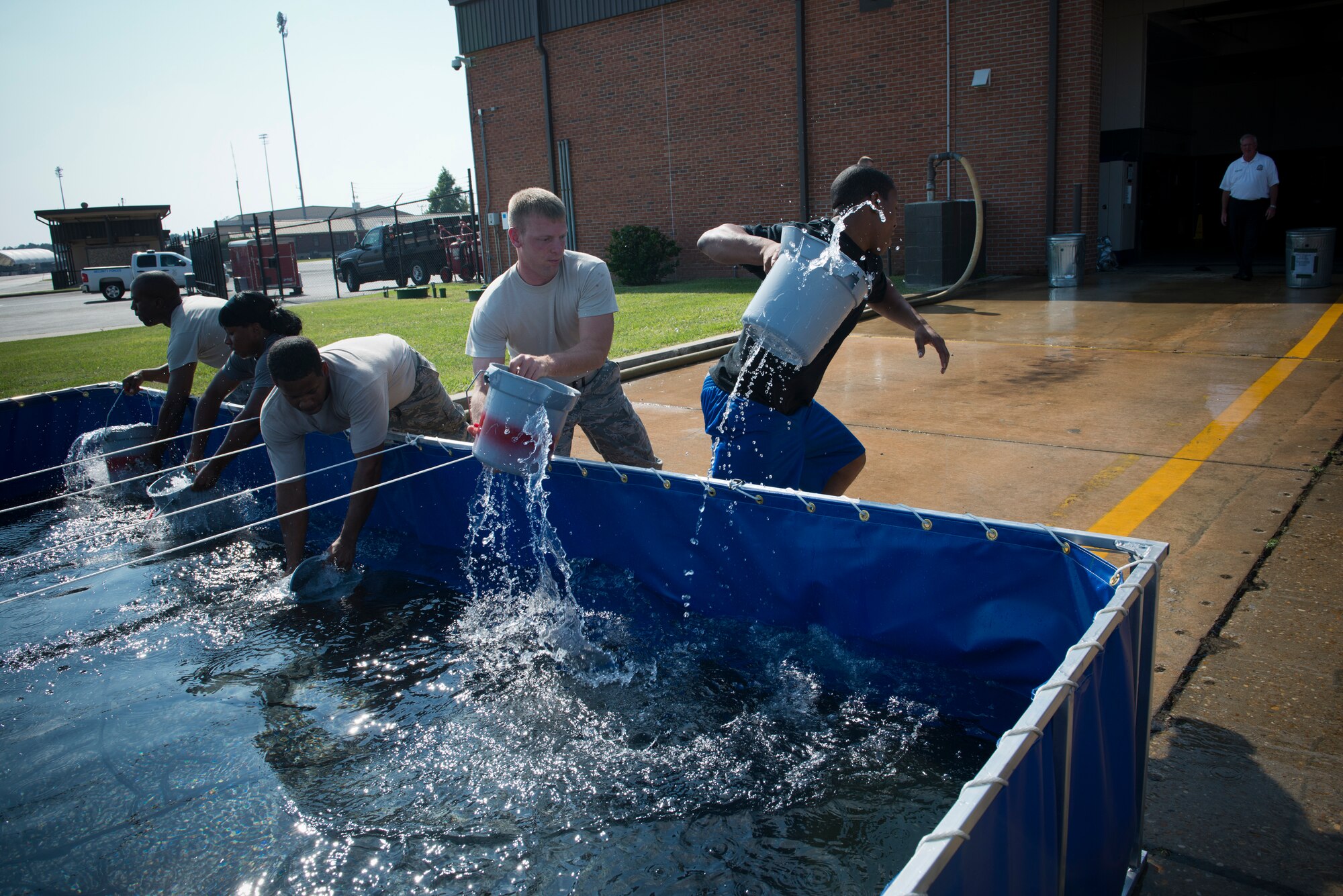 Airmen fill buckets with water during a Fire Muster Challenge at Moody Air Force Base, Ga., Oct. 12, 2012. The Airmen used buckets of water to fill aluminum cans, staged 25 feet away. The cumulative time for completing all activities determined the winner. (U.S. Air Force photo by Senior Airman Douglas Ellis/Released)
