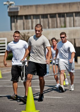 A team of four carries a ladder around the cones during the annual fire muster challenge that concluded fire prevention week at Eglin Air Force Base, Fla., Oct. 12.  Teams competed in the challenge that included a team ladder carry, fire hose roll up, victim-carry and water relay.  (U.S. Air Force photo/Samuel King Jr.)
