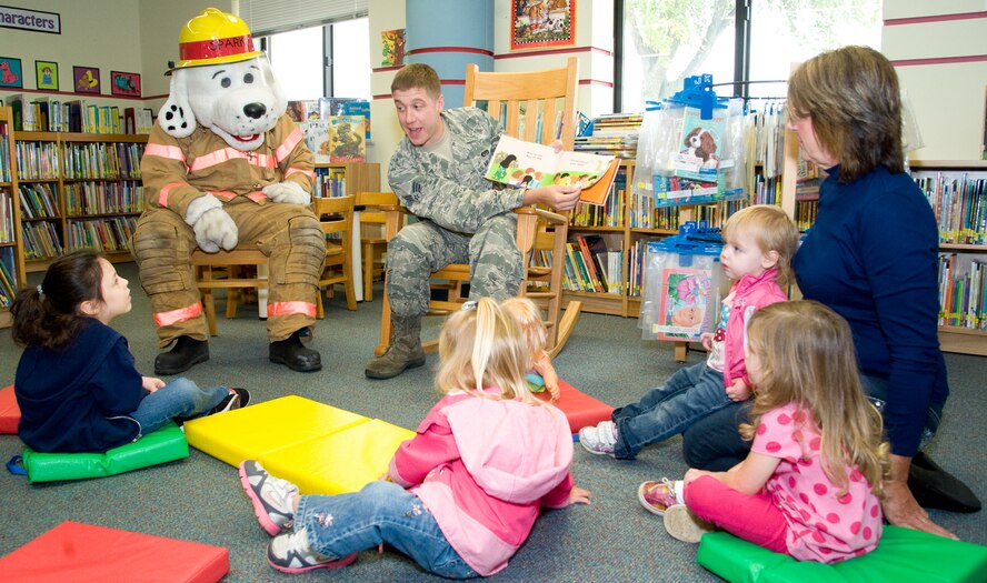 Senior Airman Scott Madara, a firefighter with the 436th Civil Engineer Squadron Fire Department, and Sparky the Fire Dog read to children Oct. 10, 2012, at the base library at Dover Air Force Base, Del. Members of the fire department read to the children in honor of Fire Prevention Week. (U.S. Air Force photo by Adrian R. Rowan)