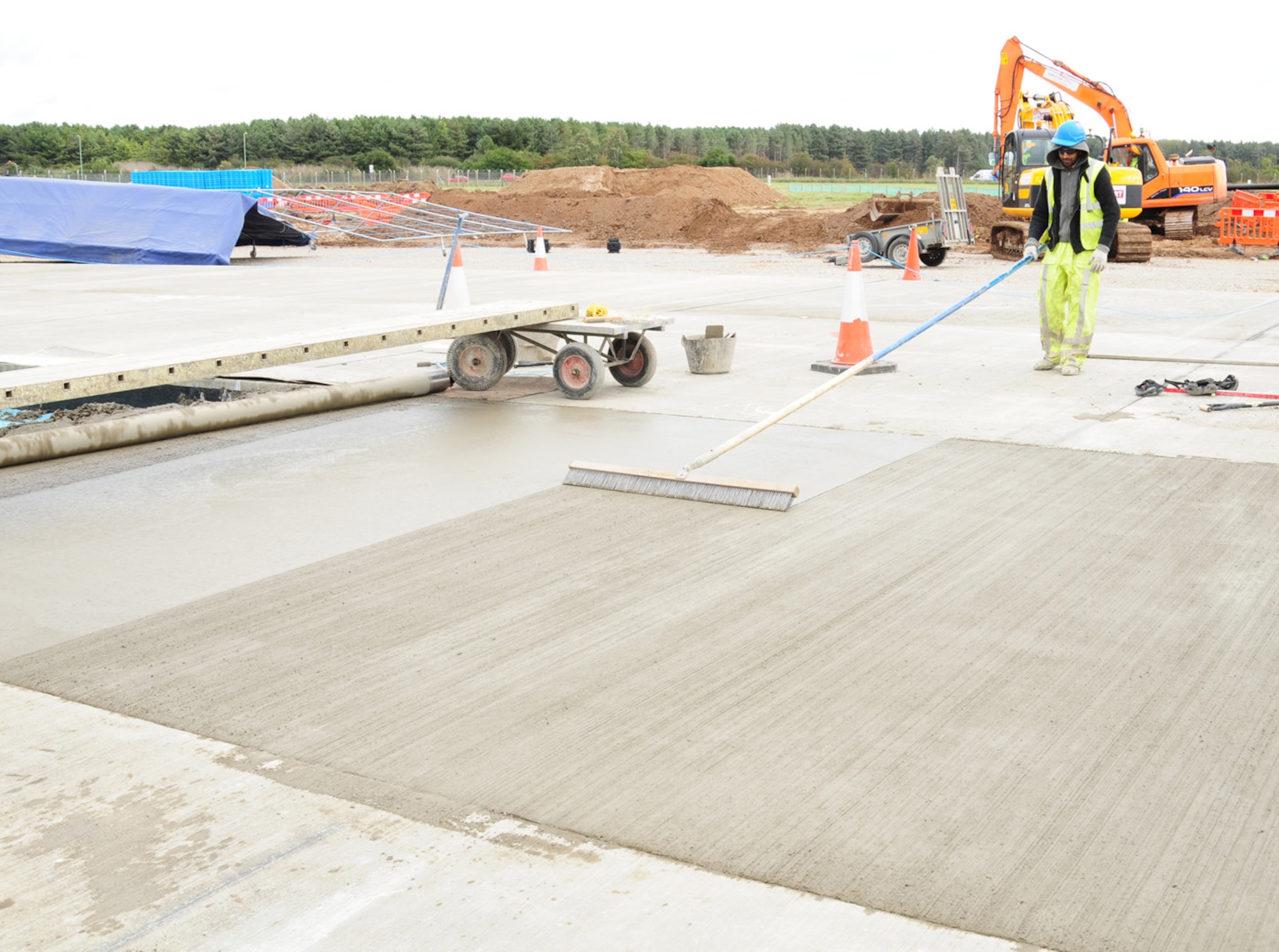A contractor uses a brush to put the final texture on the runway extension of Taxiway Alpha Oct. 5, 2012, at RAF Mildenhall, England. Pavement-quality concrete is used to provide the necessary grip required for aircraft. The extension, scheduled to be finished in April 2013, will allow swifter takeoffs for heavier aircraft, which currently have to back-taxi to the end of the overrun and turn around. (U.S. Air Force photo/Karen Abeyasekere/Released)