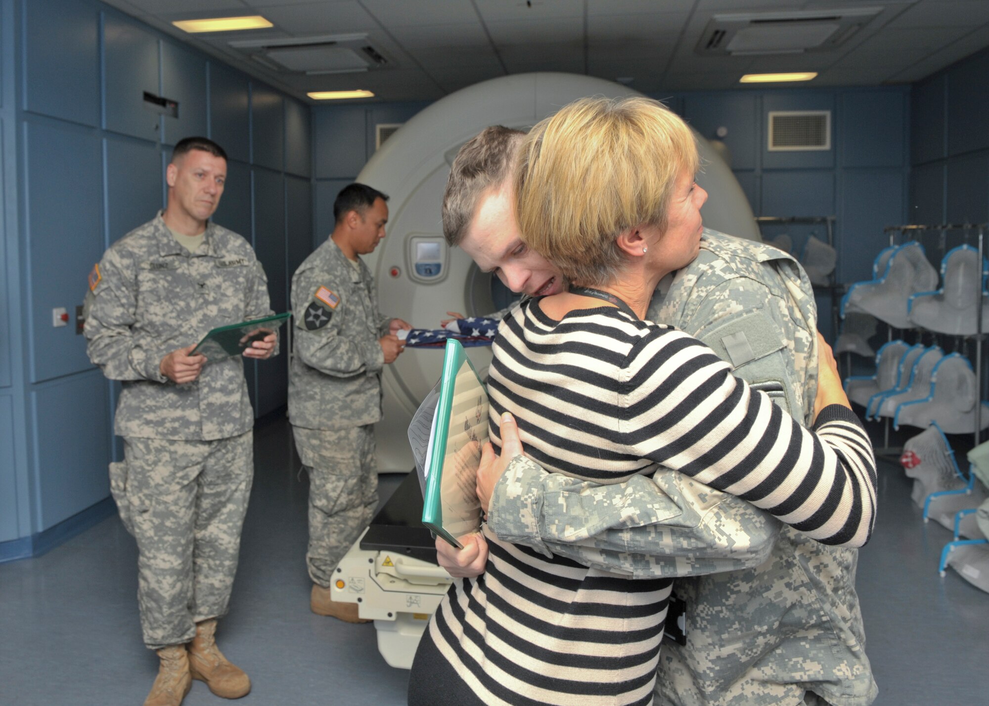 CAMBRIDGE, United Kingdom - U.S. Army Sgt.1st Class Jason Stanford is congratulated on his re-enlistment by Dr. Sarah Jefferies, his oncologist, in front of a radiology machine at Addenbrookes Hospital Cambridge, United Kingdom, as Col. Matthew P. Glunz, United States European Command Joint Intelligence Operations Center - Europe Analytic Center commander, looks on. Stanford has been under Dr. Jefferies care since early 2011. (U.S. Air Force photo by Staff Sgt. Javier Cruz)
