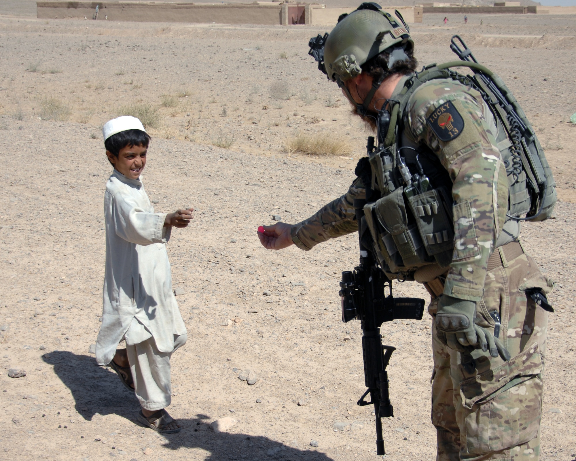 An Airman offers a small, rubber bouncy toy ball to a young man during humanitarian aid mission visit to the a local village. Airmen routinely stock up on supplies that can be donated to the communities to help strengthen coalition relationships with community members. (U.S. Air Force photo/Master Sgt. Russell Martin)