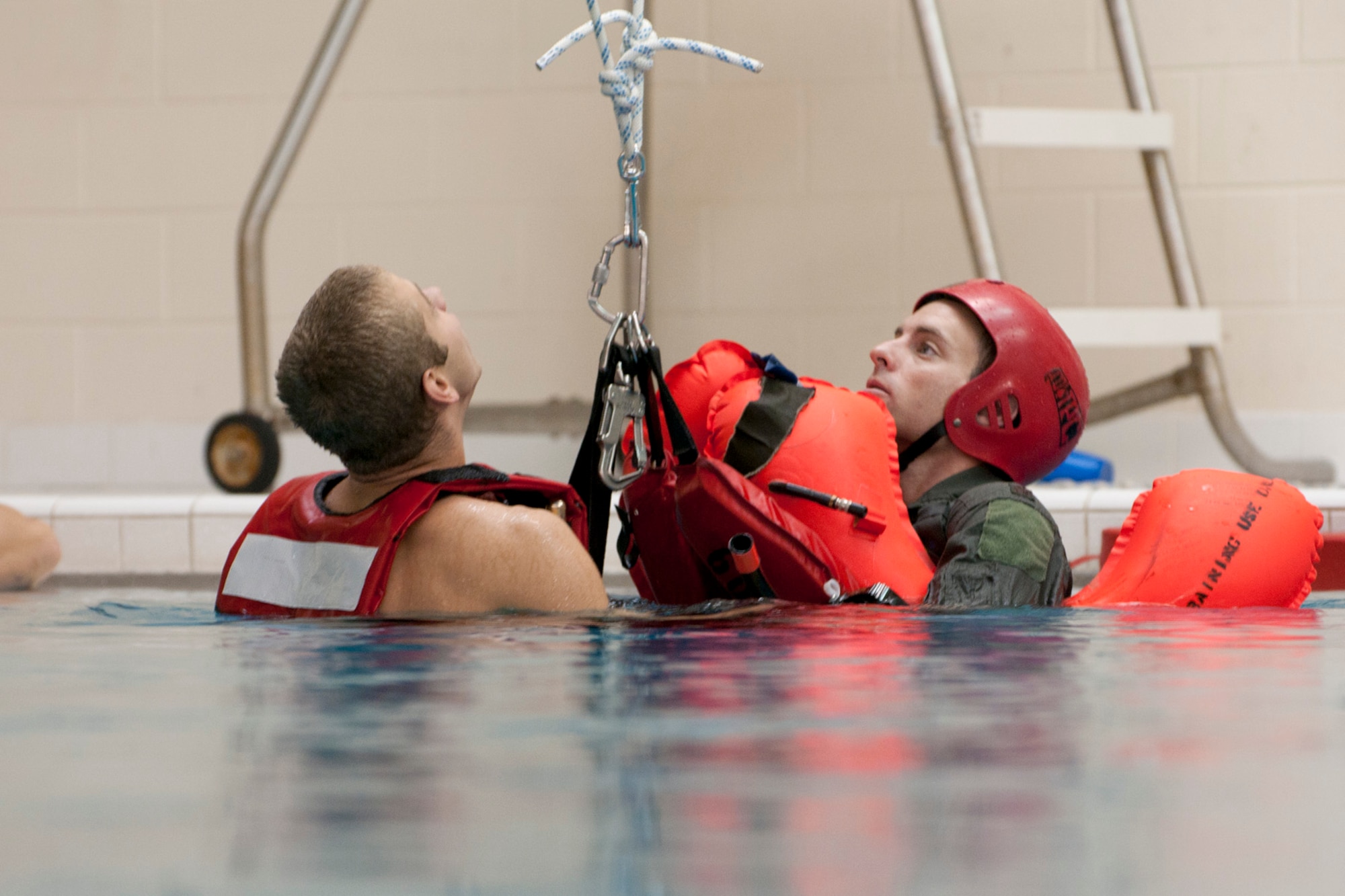 Capt. Daniel Totsch, a pilot with the 171st Air Refueling Squadron, right, prepares to be hoisted out of the water while in a sling with U.S. Coast Guard rescue swimmer AST3 Robin Pietschmann from Coast Guard Air Station Detroit. The 171st ARS conducted water survival training in the pool of L’Anse Cruese North High School, near Selfridge Air National Guard Base, Mich., Oct. 16, 2012. Since Air Force air crews operate in a worldwide environment, they must train for every contingency scenario, including the possibility of a downed aircraft in an ocean or lake.  The 171st flies the KC-135 Stratotanker, which can carry approximately 50 passengers. (Air National Guard photo by TSgt. Robert Hanet)