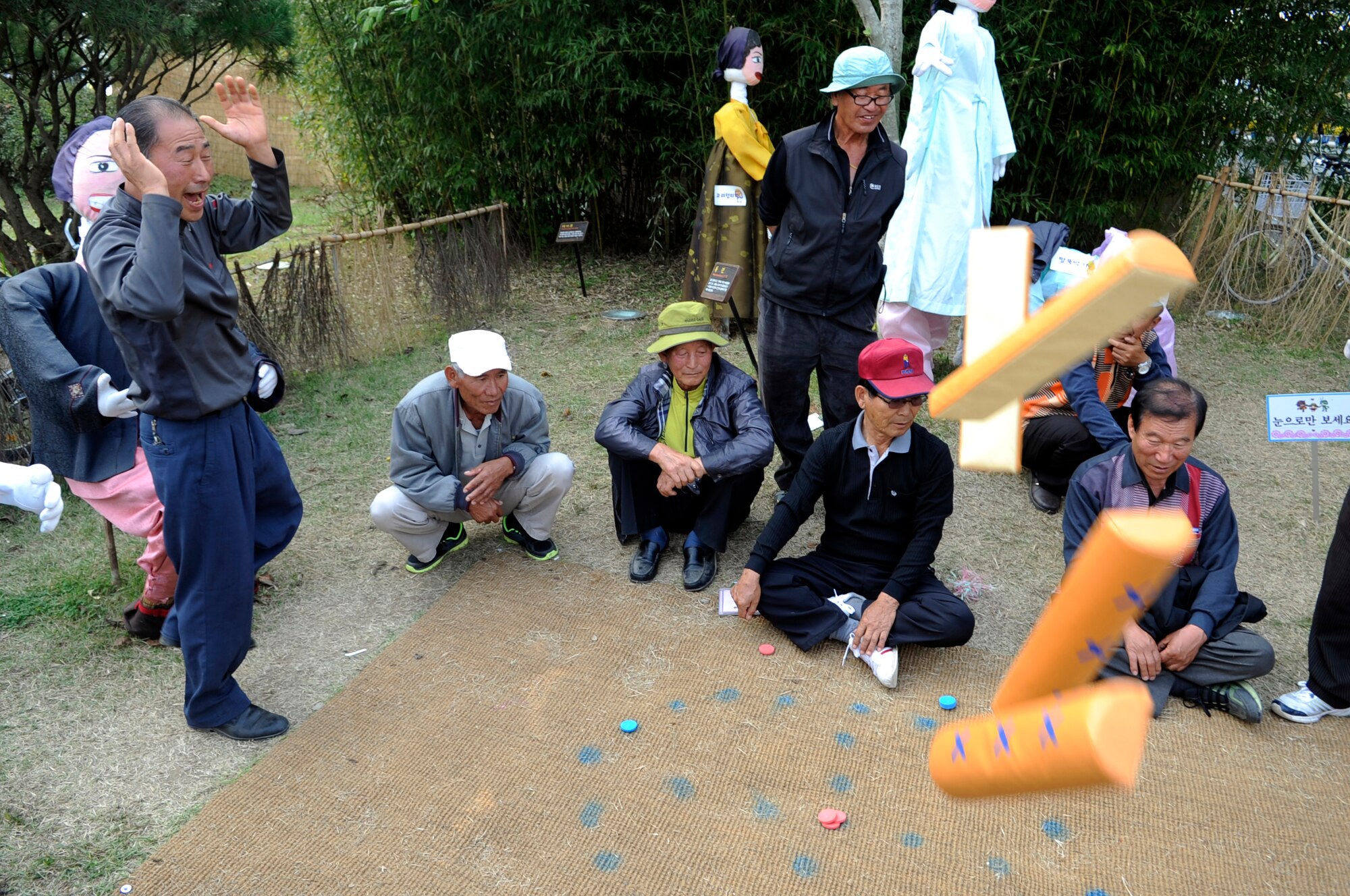 Men at the Gimje Horizon Festival play a traditional Korean game Oct. 14, 2012, in Gimje, South Korea. The number of spots they get to move around the circle depends on how many of the orange playing pieces land with the flat side up.  (U.S. Air Force photo/Senior Airman Brigitte N. Brantley)