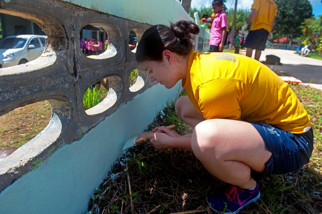 U.S. Navy Lt. j.g. Bridget Riordan helps paint the wall that surrounds the Baan Klong Sai school during a community service project in Phuket, Thailand, Oct. 10, 2012. Riordan is assigned to the USS Mobile Bay.